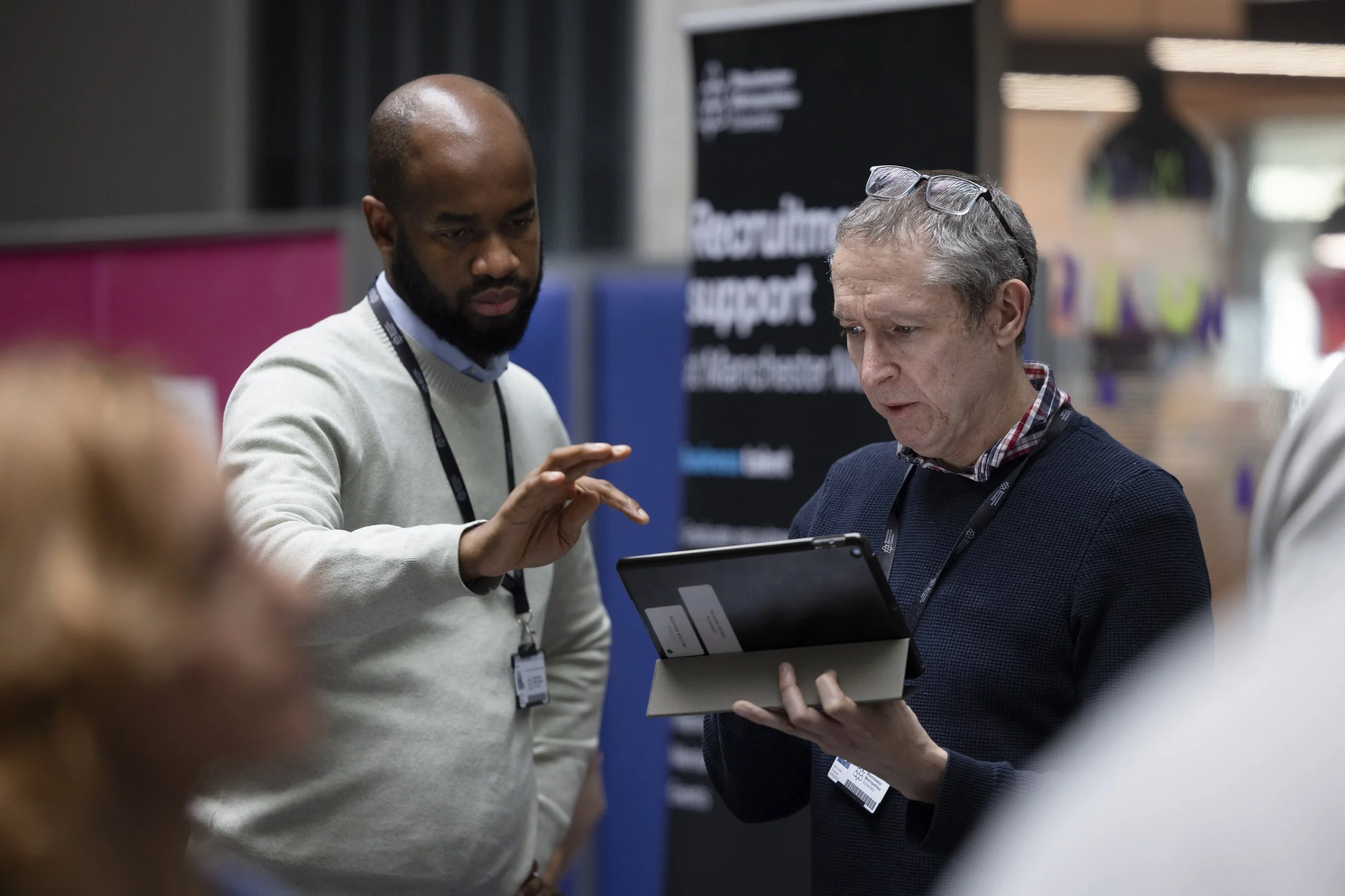 two men look at data on a laptop at a conference in Manchester