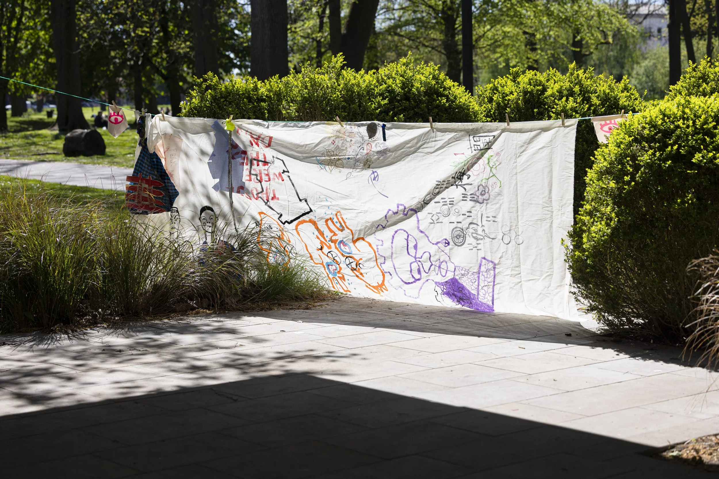 Painted textile artwork drying on a washing line in Whitworth Park, Manchester, part of an upcycling and experimental textile workshop led by contemporary artists