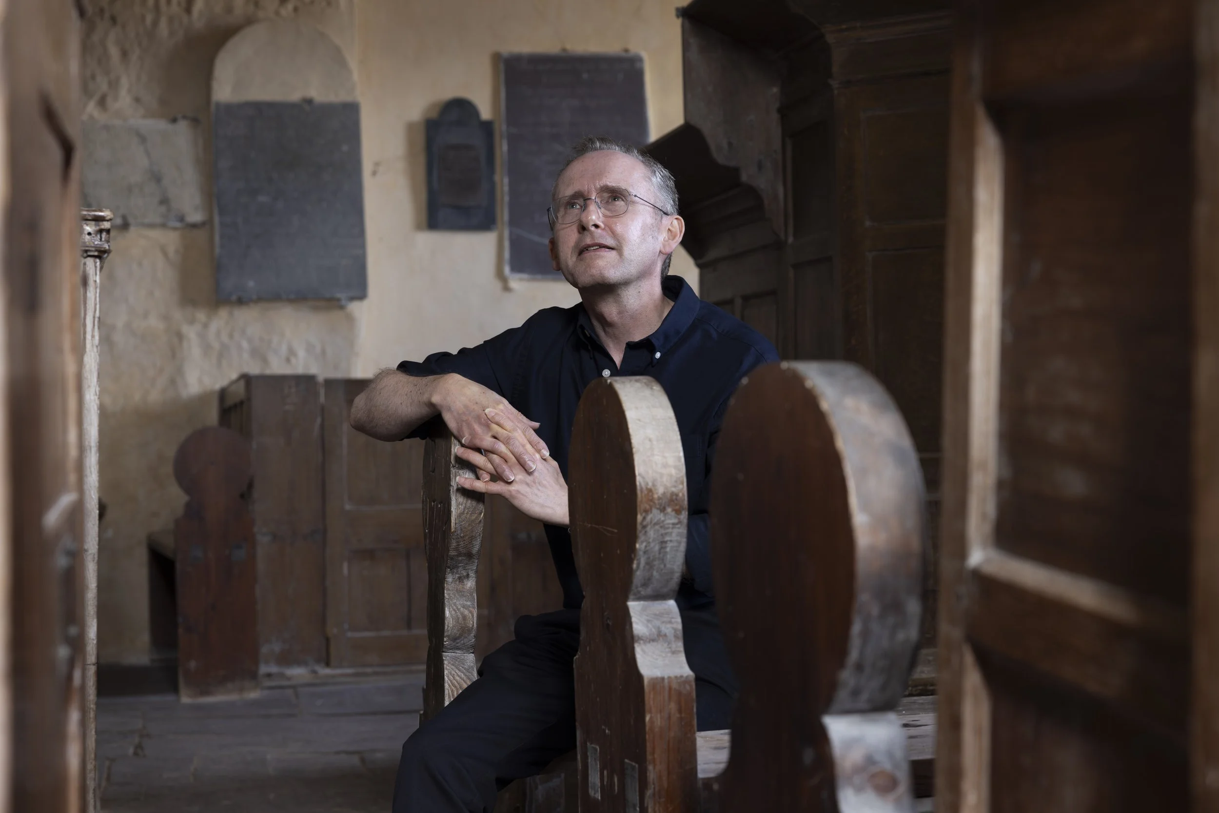 David Farrington sitting on a pew inside St Baglan’s Church.