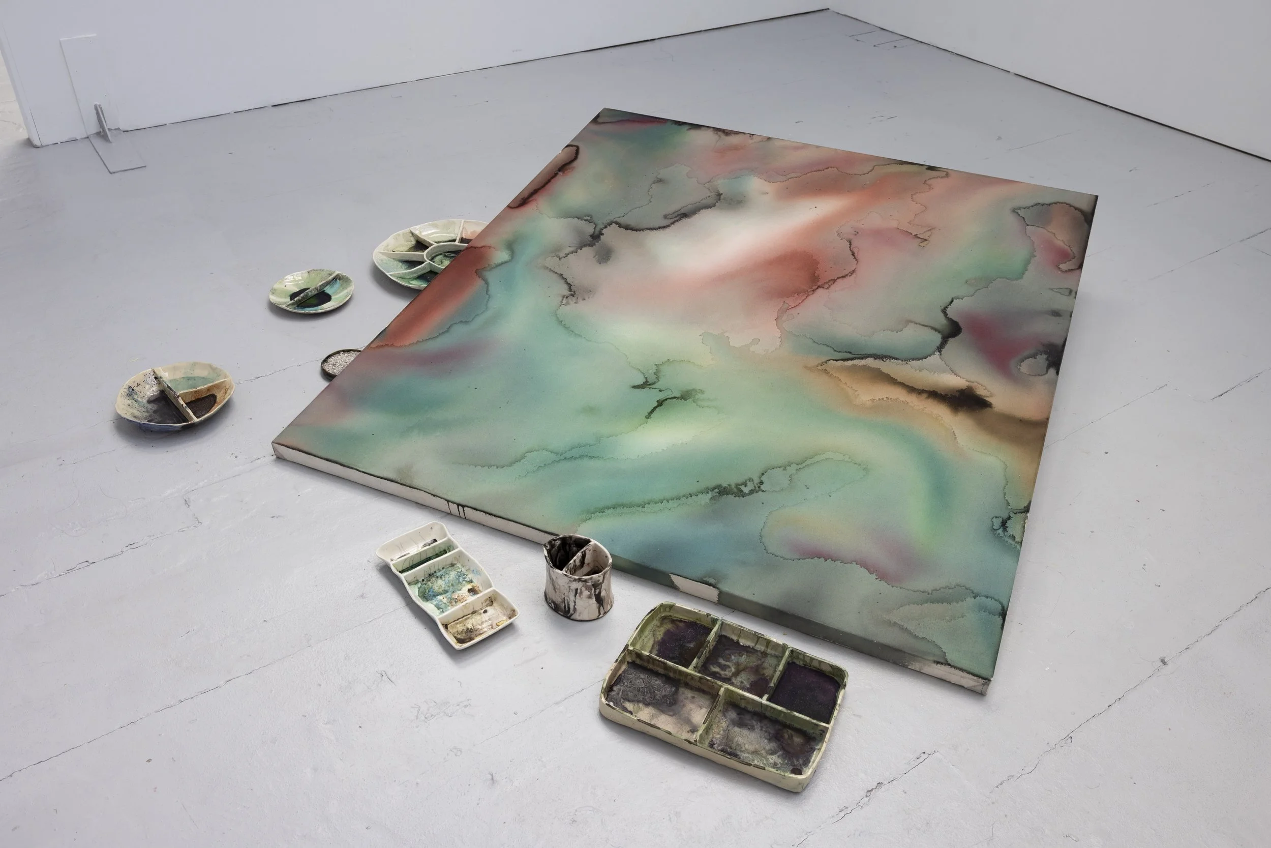 A painting displayed on the floor along with ceramic paint containers during the Manchester School of Art's 2026 final year show