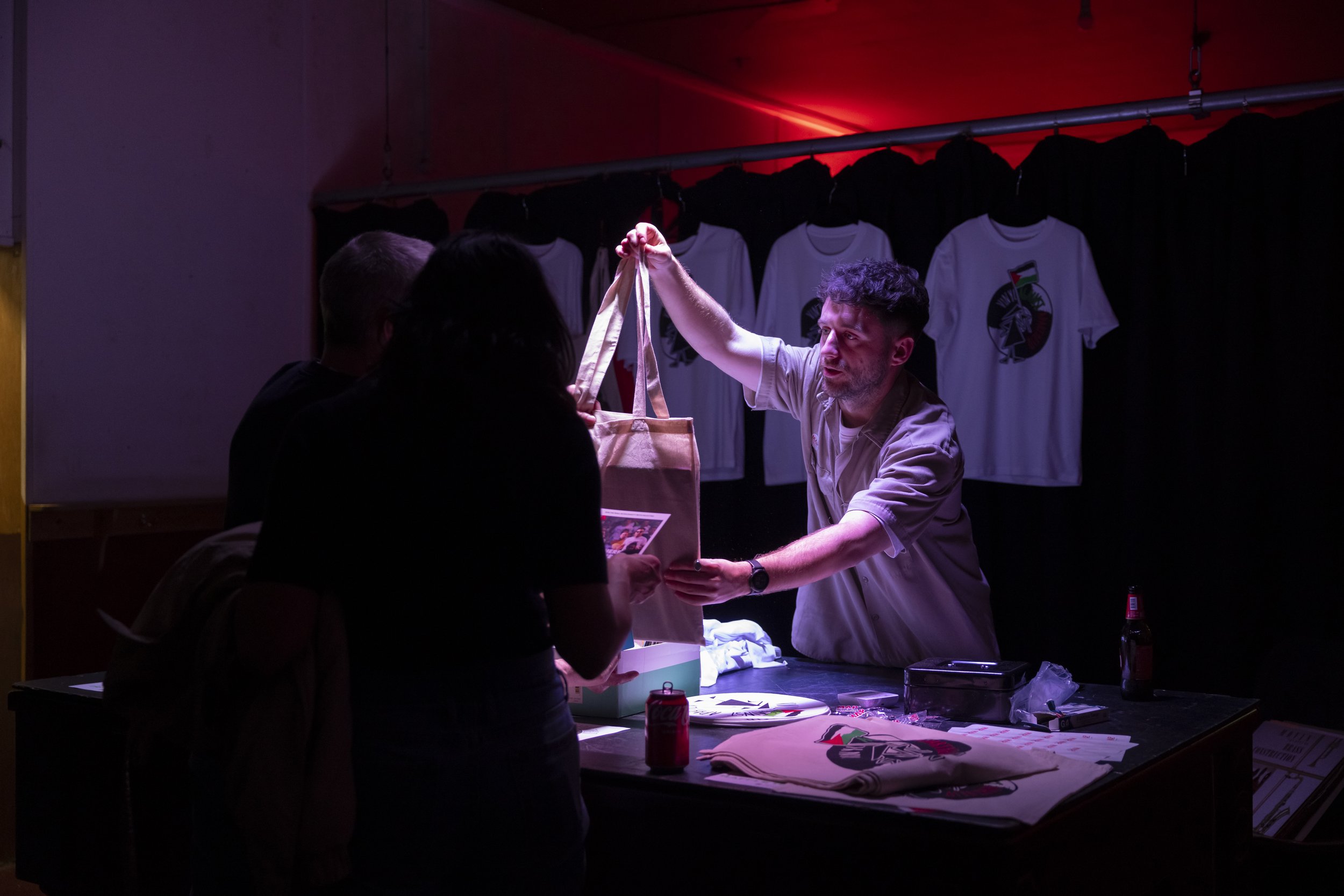 Staff handing tote bag of vinyl records to attendee at Manchester charity fundraising event