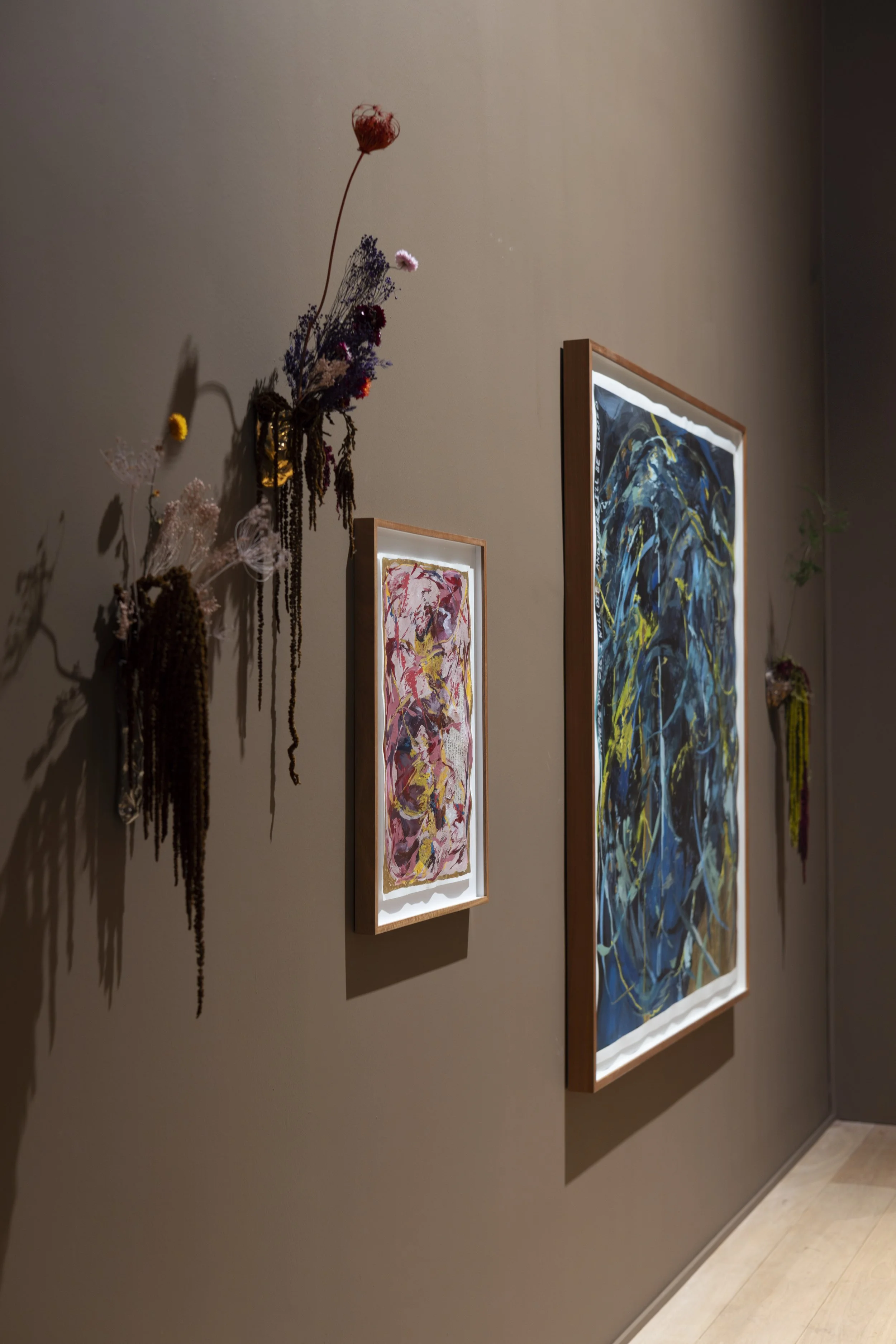 Art installation featuring two canvases with floral arrangements as part of exhibition display.