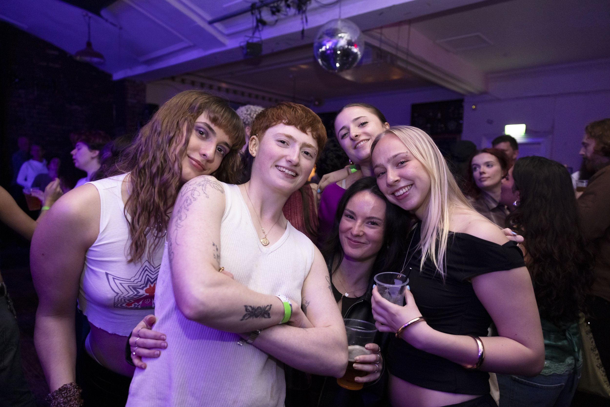 Group of friends posing and dancing on packed dancefloor at Manchester event photography shoot