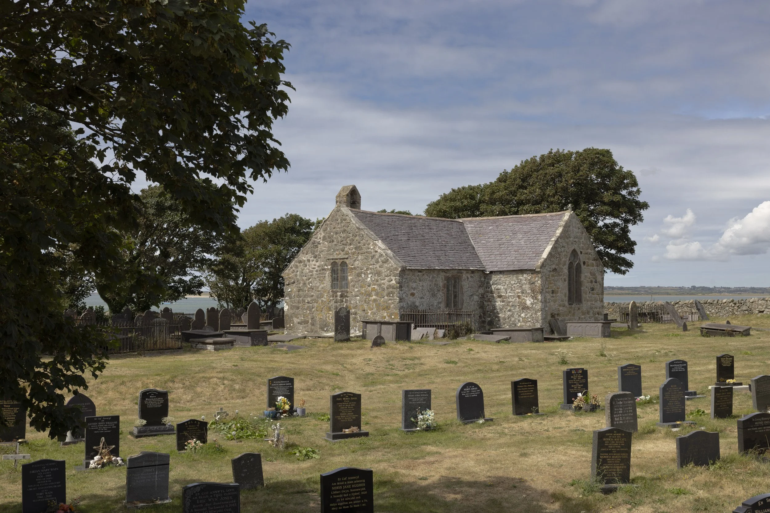 St Baglan’s Church with the Menai Strait visible in the distance beyond the surrounding landscape.