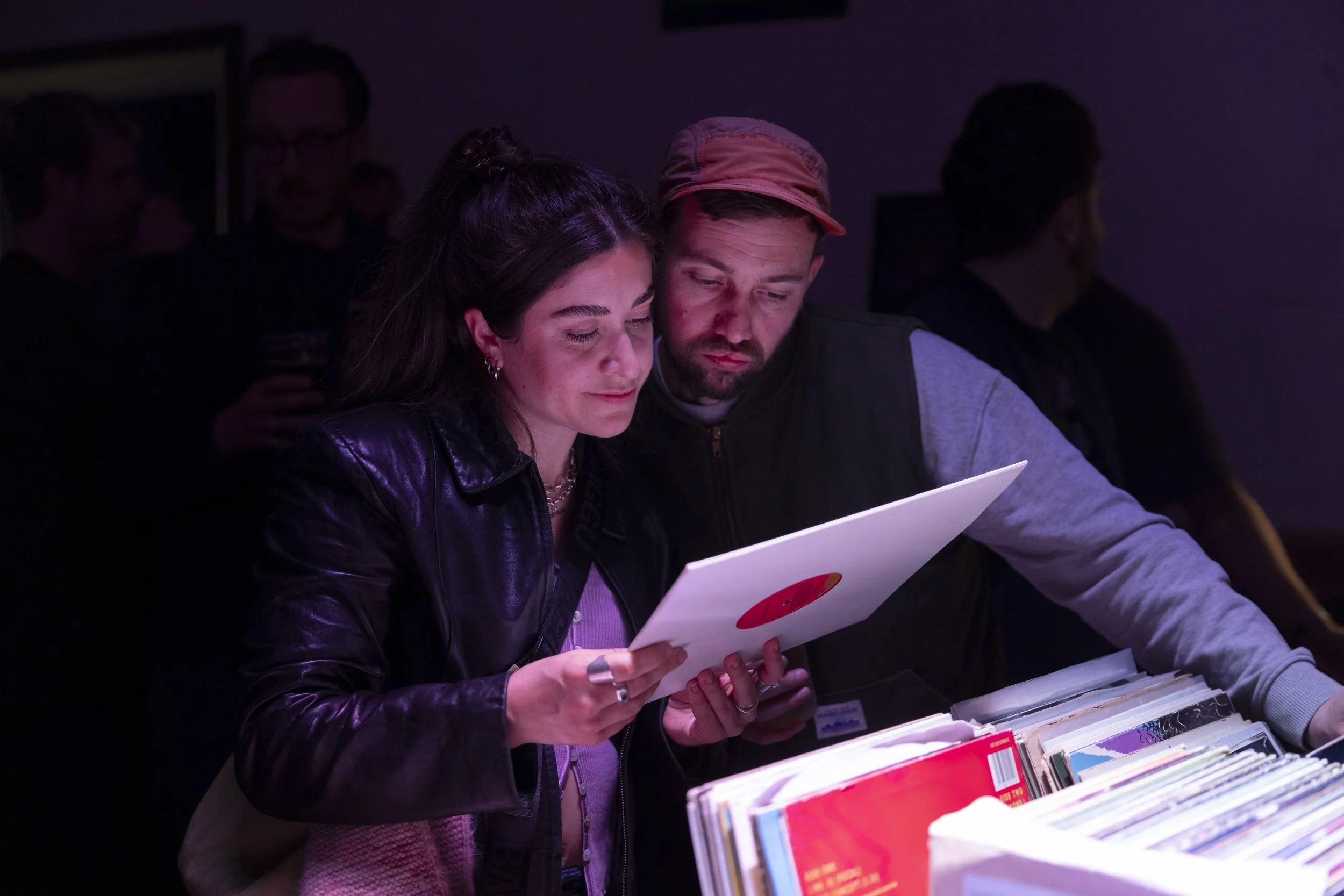 Couple reading vinyl record labels while crate digging at Manchester fundraising music night