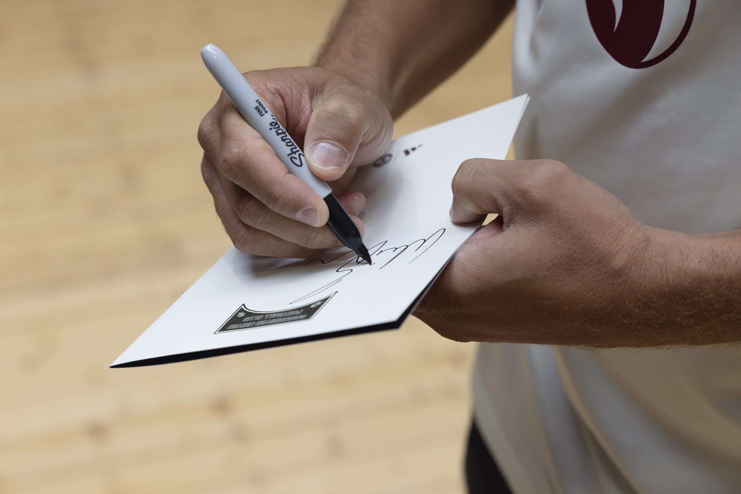 Close-up of former Manchester United player Wes Brown signing a Salford Lads & Girls Club document.
