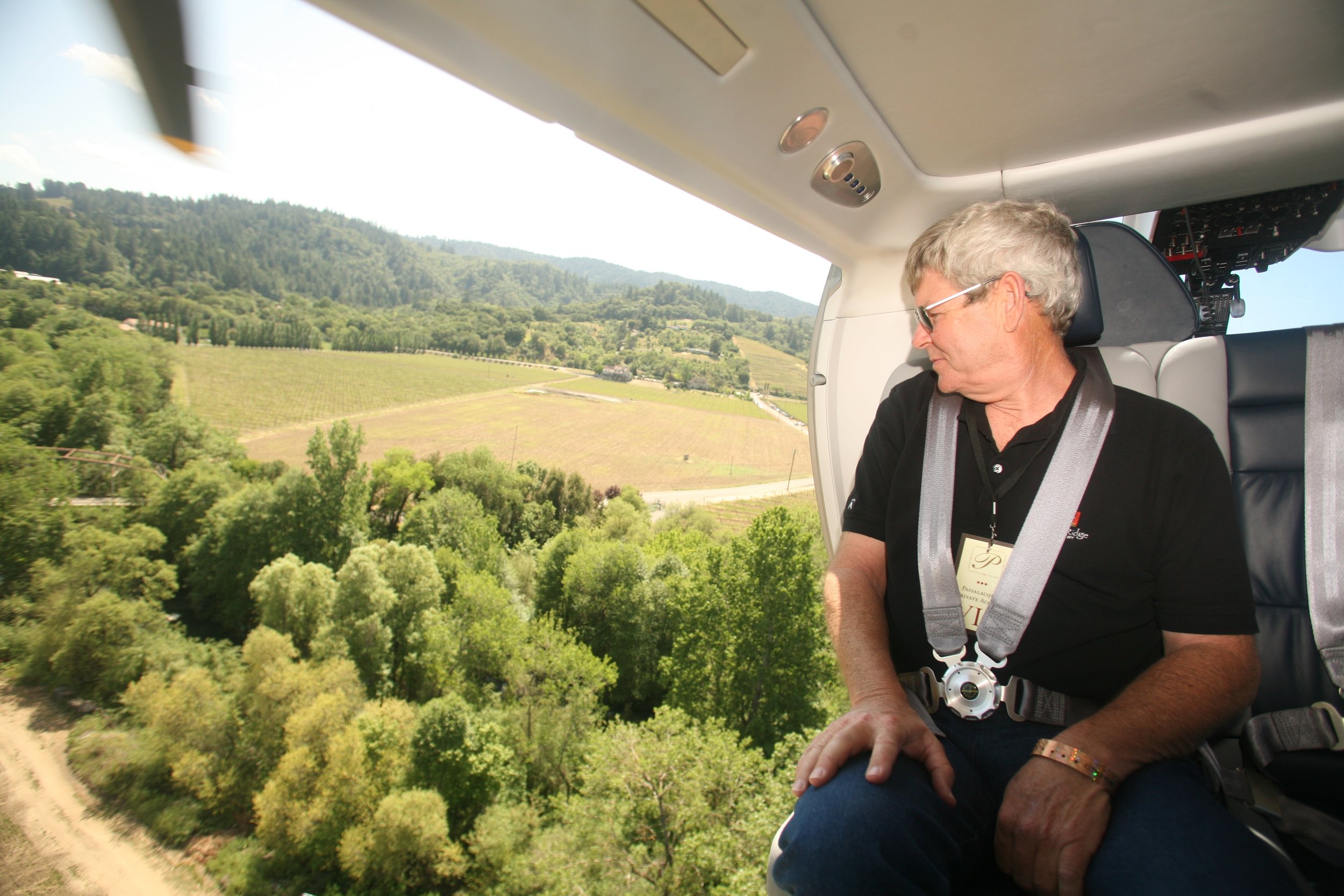 Woman looking down at winery from open flying helicopter door