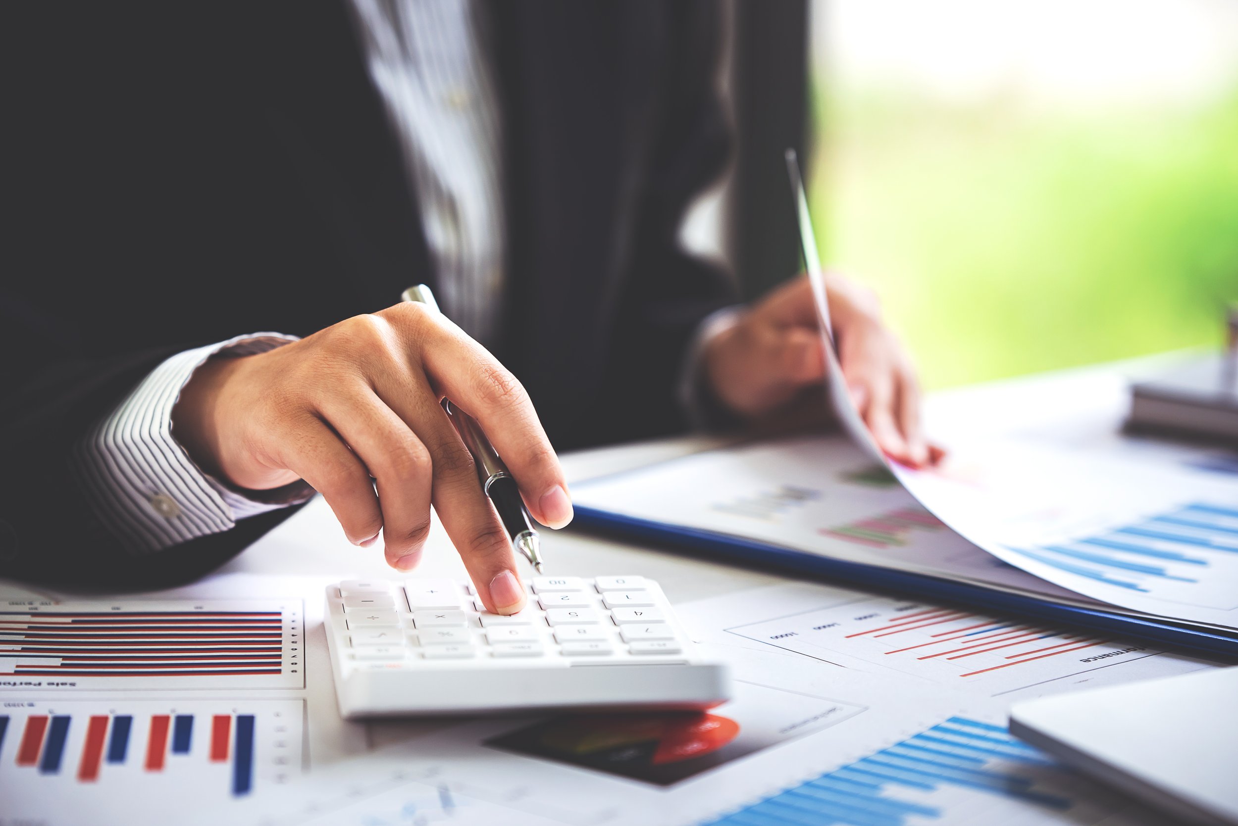 A property manager reviewing financial reports and using a calculator to assess rental income and expenses.