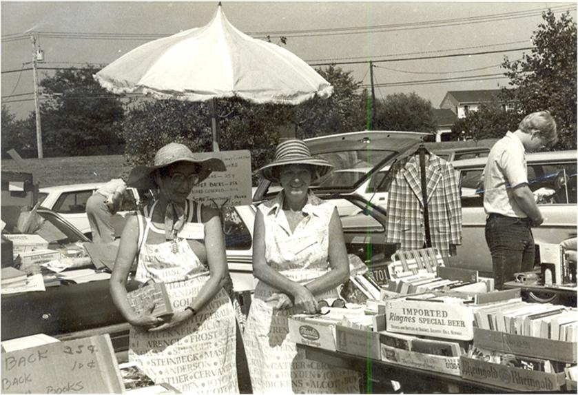 The Friends of the West Windsor Library is proud to celebrate its 37th Year. Above is our first book sale. West Windsor’s First Branch Library The Mercer County Library System (MCLS) opened a branch library in West Windsor Township (WWT) in November 1968. The library was located in a leased vacant school building, built in 1882, located on Village Rd in Dutchneck. (This building is currently used by the West Windsor-Plainsboro School District.) The useable space was 2,482 sq. ft. The Library quickly filled this space, as the Township’s population grew. By the mid 1970’s it became clear that the space was inadequate. In 1978 conversations commenced between MCLS and WWT Ad Hoc Library Committee (Library Committee) regarding future library needs. The Library Committee recommended building a 5,000 sq. ft. library, with meeting rooms, and a separate area for children. In early 1980, the West Windsor Township Council asked the Library Committee to organize a “friends group” to help with the organization of a new library. Friends of the Library (FOL) groups already were plentiful in the US and dated back to 1922. The Friends groups were formed for the purpose of fundraising for the library, drafting volunteers, and running community programs. Friends of the West Windsor Library Campaign Begins The Library Committee began a Friends of the West Windsor Library (FOWWL) publicity campaign and posted a membership signup sheet in the Library. In June, 1980 Mercer County's Freeholders passed a bond ordinance to enable the MCLS libraries’ expansion projects to proceed. Our Library Community was thrilled and by August 1980, 50 people had expressed interest in joining a Friends group! The Library Committee consisting of Mary Benton, Marilyn Dais, Ruth Finkelstein, Carol Gerbino, Jay Hughes, and Sylvia Russo. Interested patrons were invited to attend an FOL organizational meeting on October 5, 1980. Early Fundraising Efforts The Library Committee sold used books at West Windsor—Plainsboro High School (now South) Flea Market September 1980.