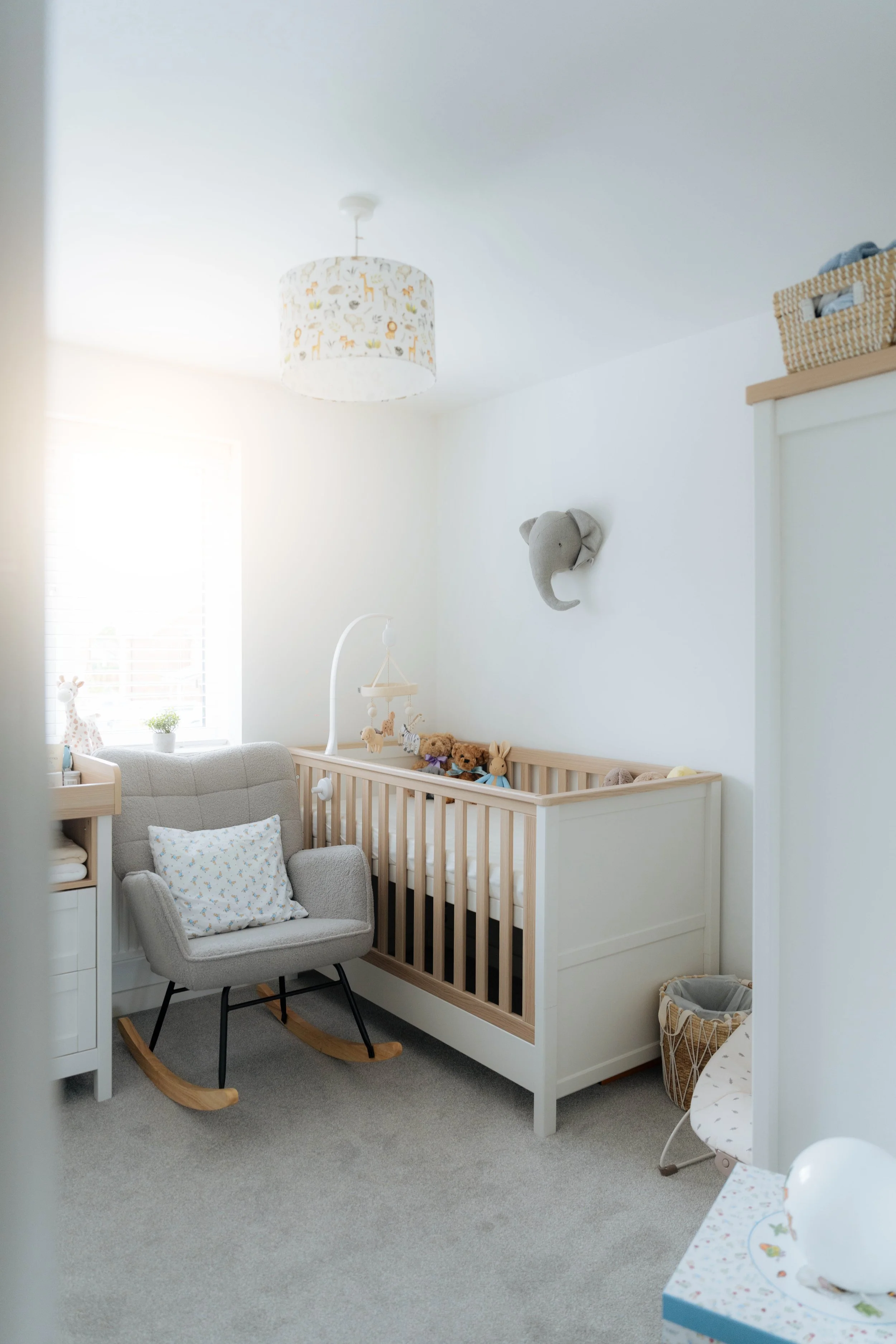 White nursery room with cot and rocking chair — newborn lifestyle photography setup