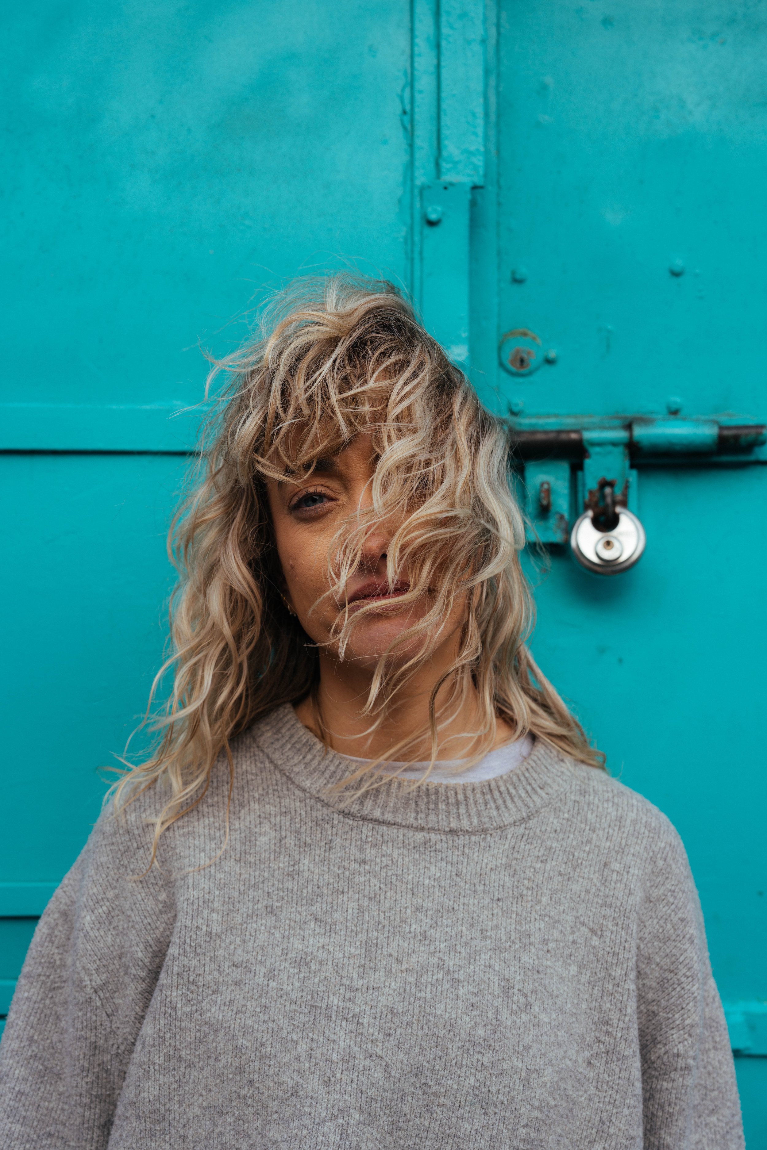 Woman portrait with curly hair against teal background — outdoor location photography