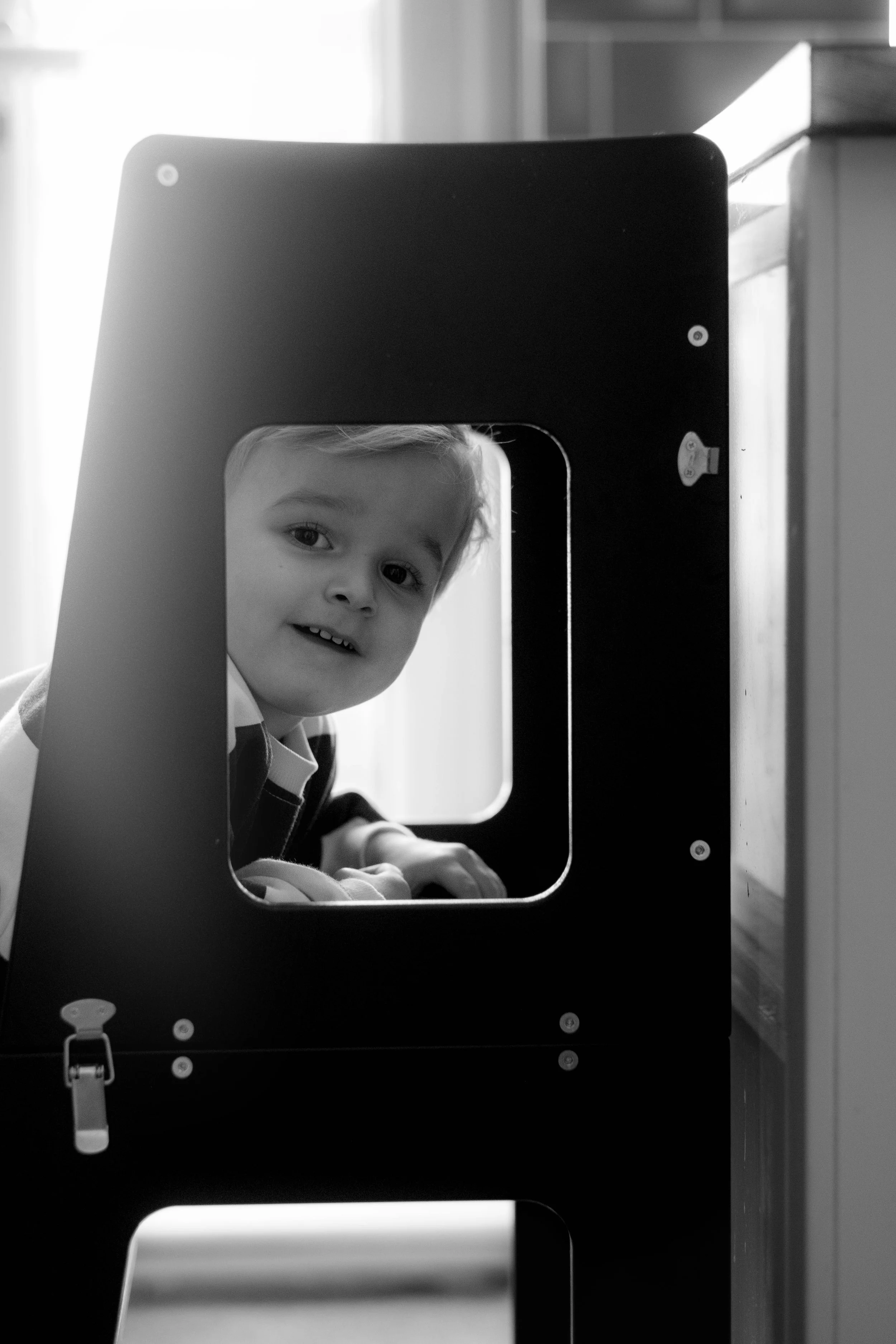 Child portrait framed through a square window — creative family photography composition