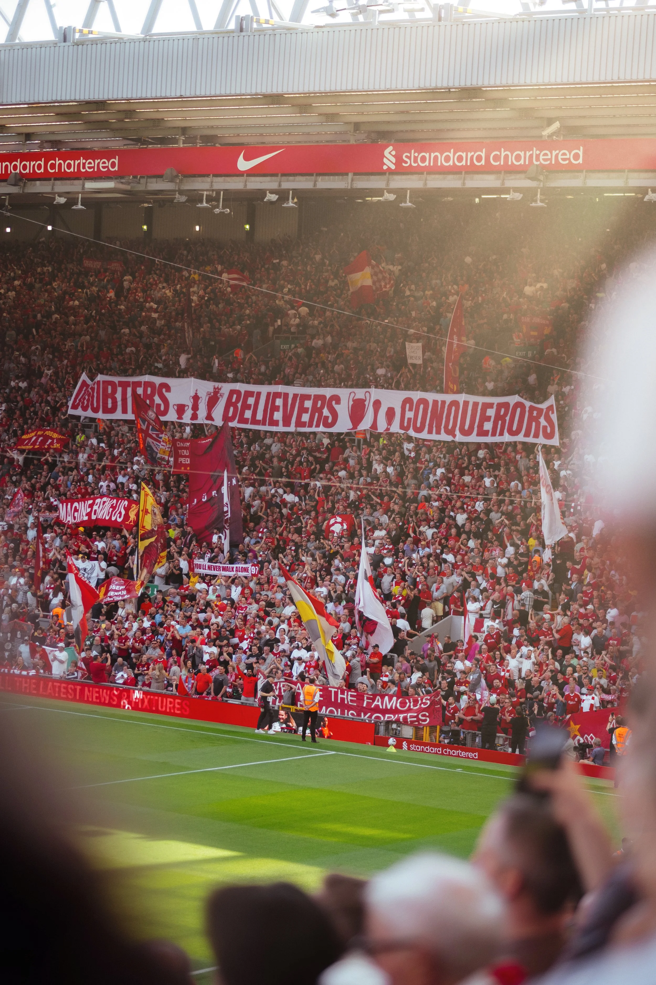 Liverpool FC fans at Anfield with red scarves and banners — match day crowd photography