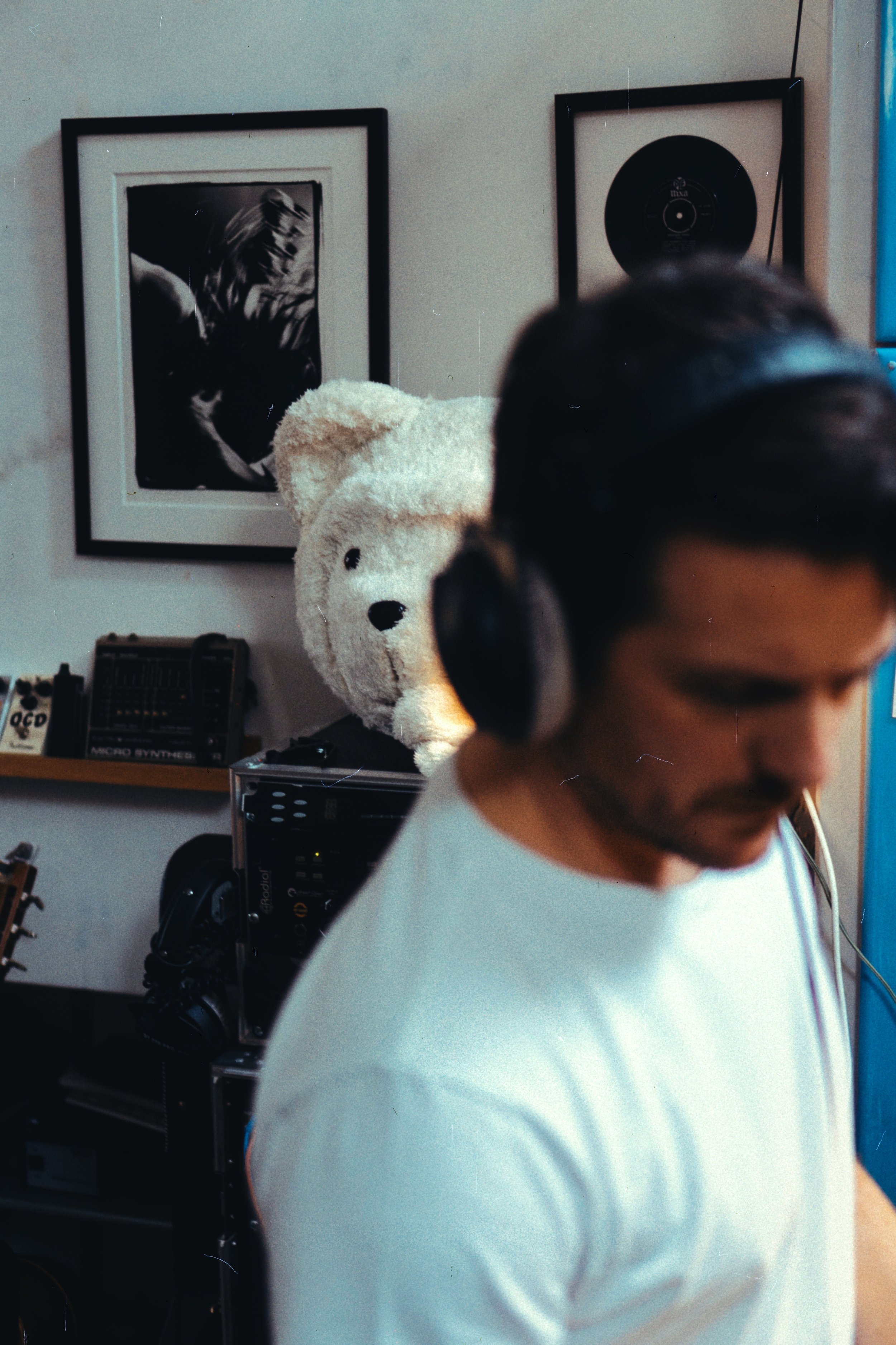 Person with headphones listening to music — teddy bear mascot in creative home studio