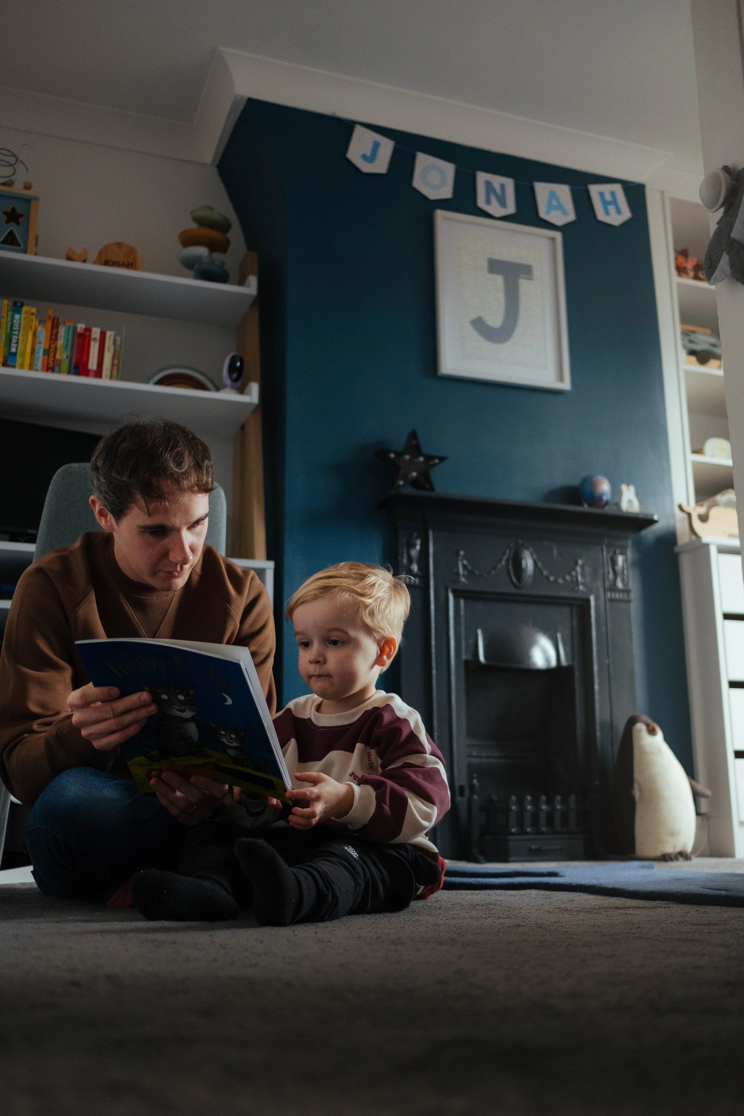 Father and son reading together by fireplace — family lifestyle photography