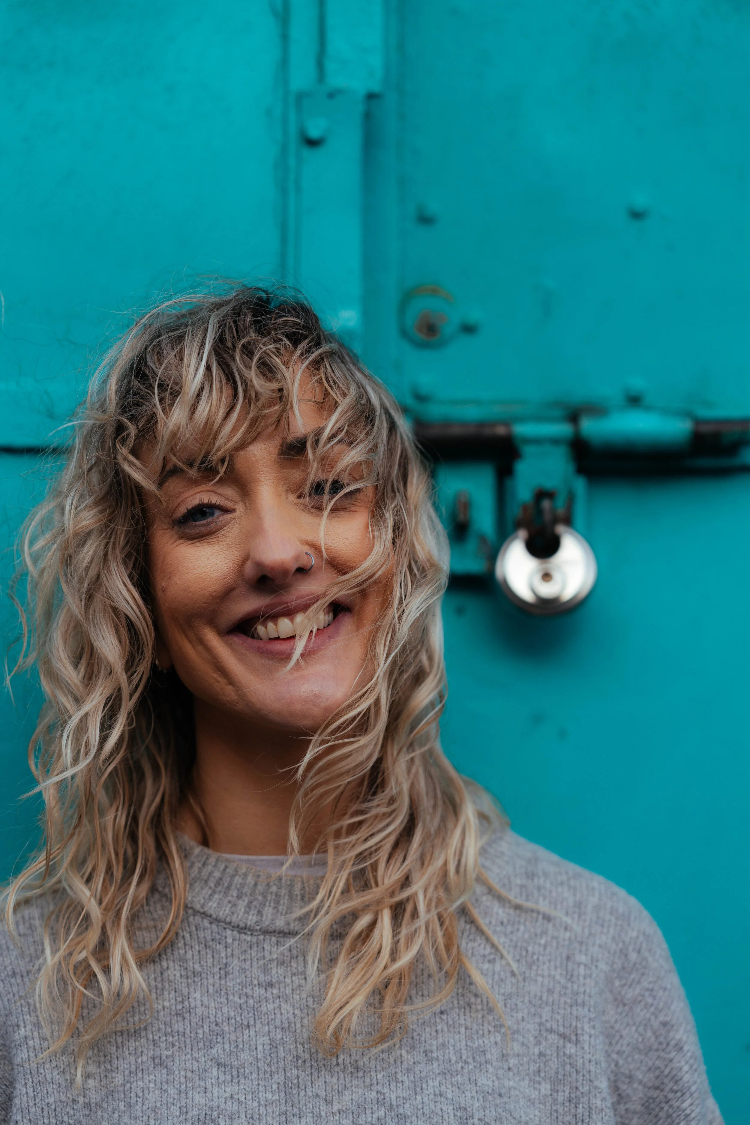 Portrait session — woman with curly hair laughing, teal background, Liverpool photographer