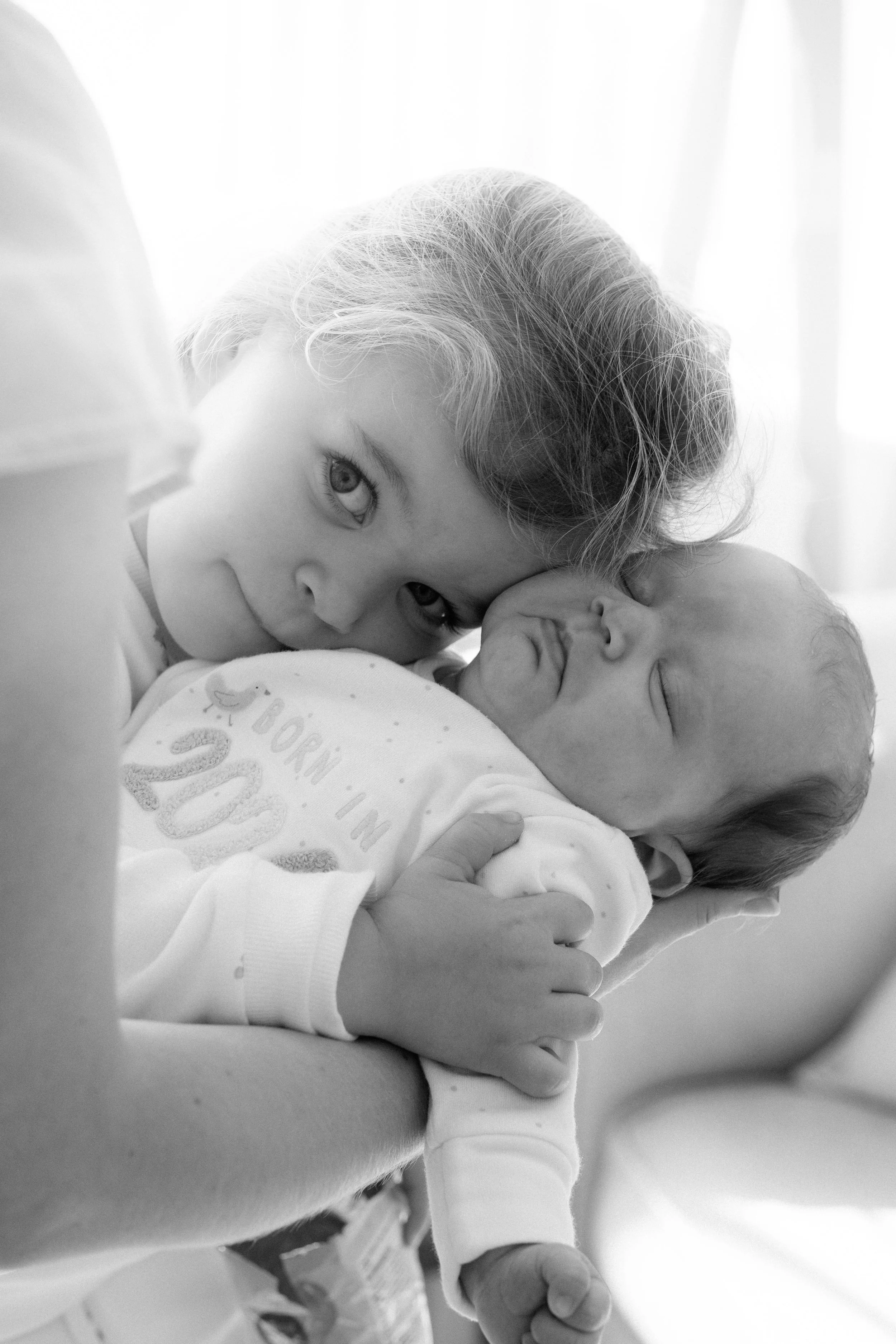 Child meeting new sibling — tender newborn family photography moment