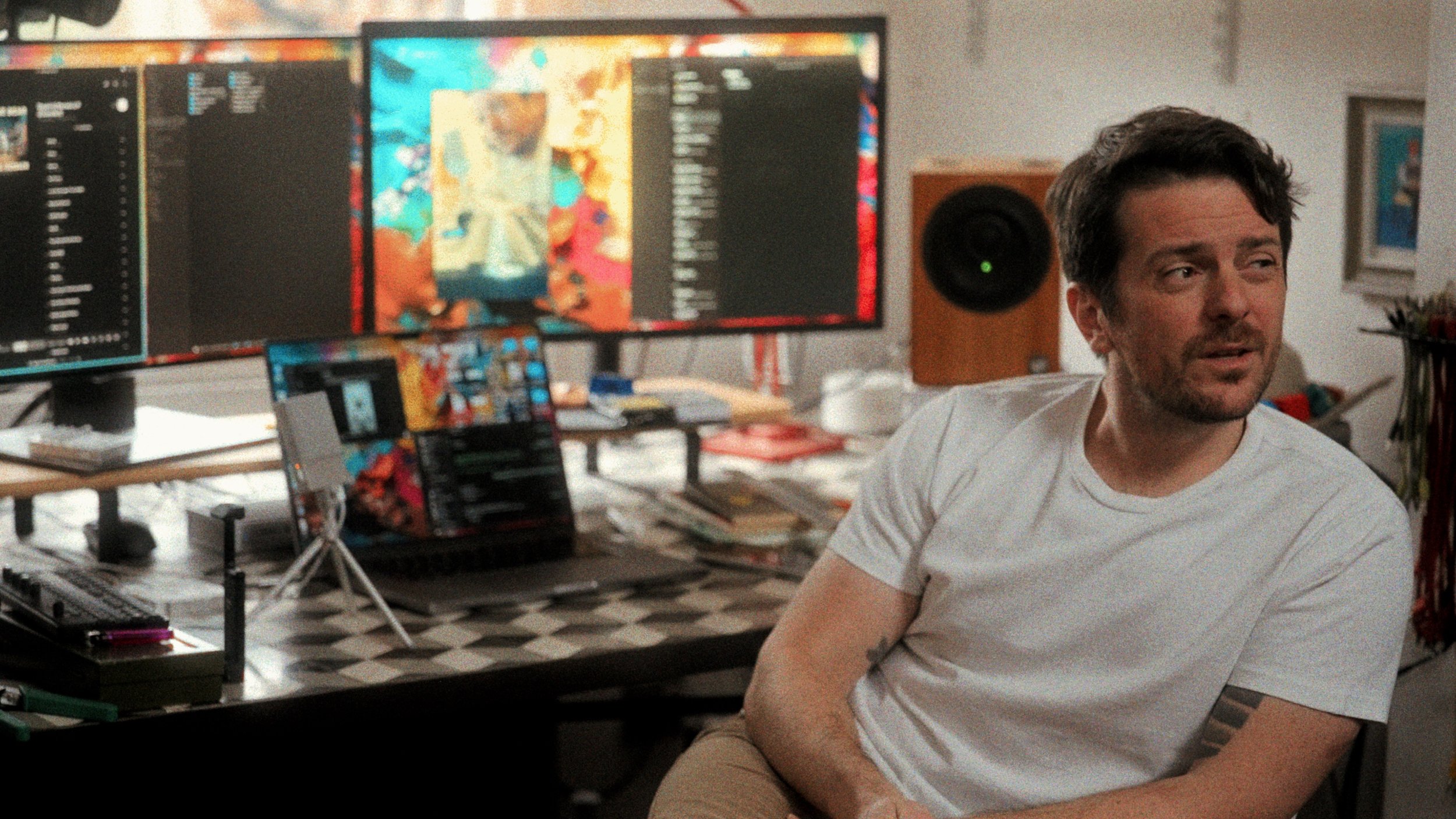 Creative director at desk with large design monitor — home studio workspace photography
