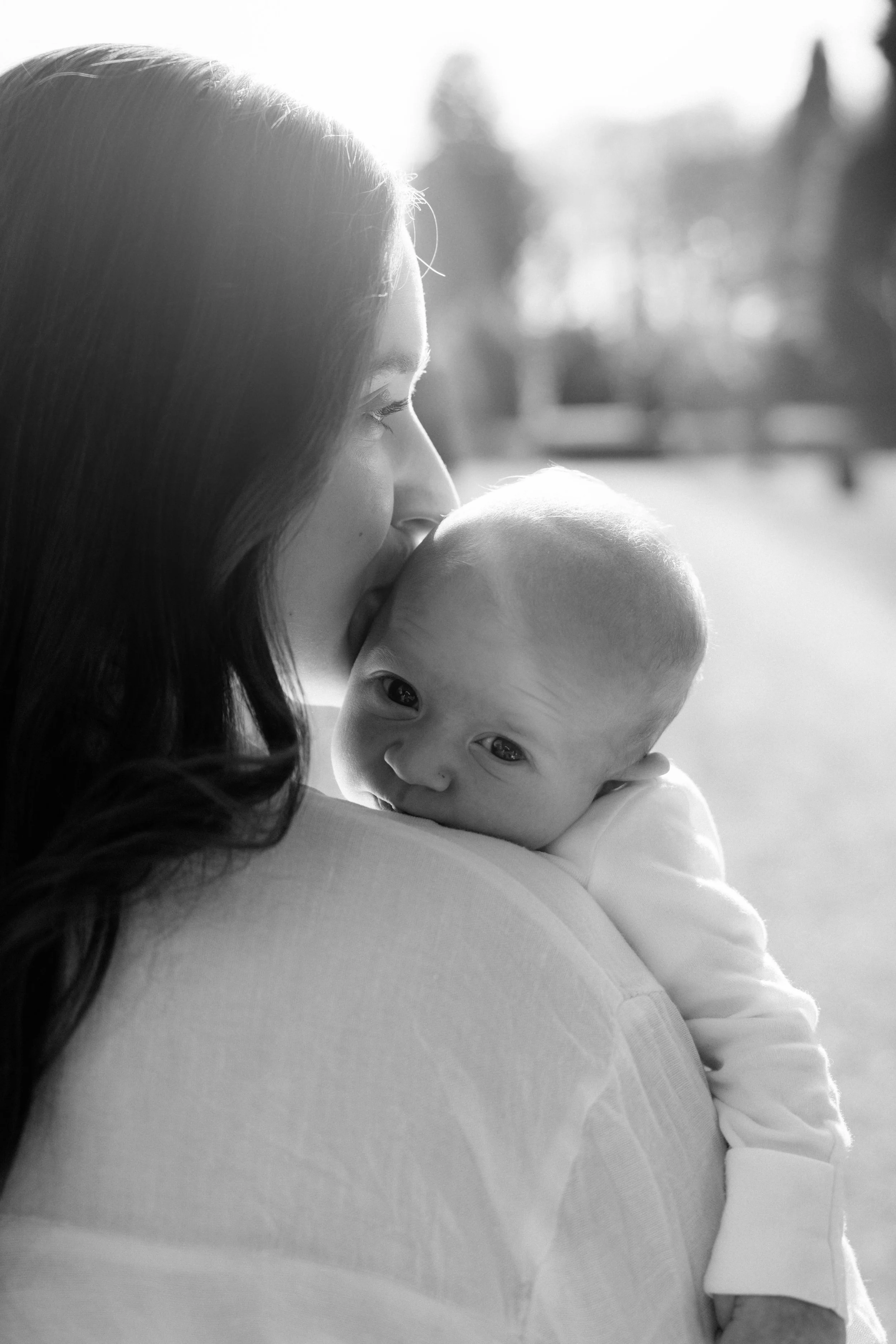 Mother cradling newborn baby, close-up — tender black and white newborn photography