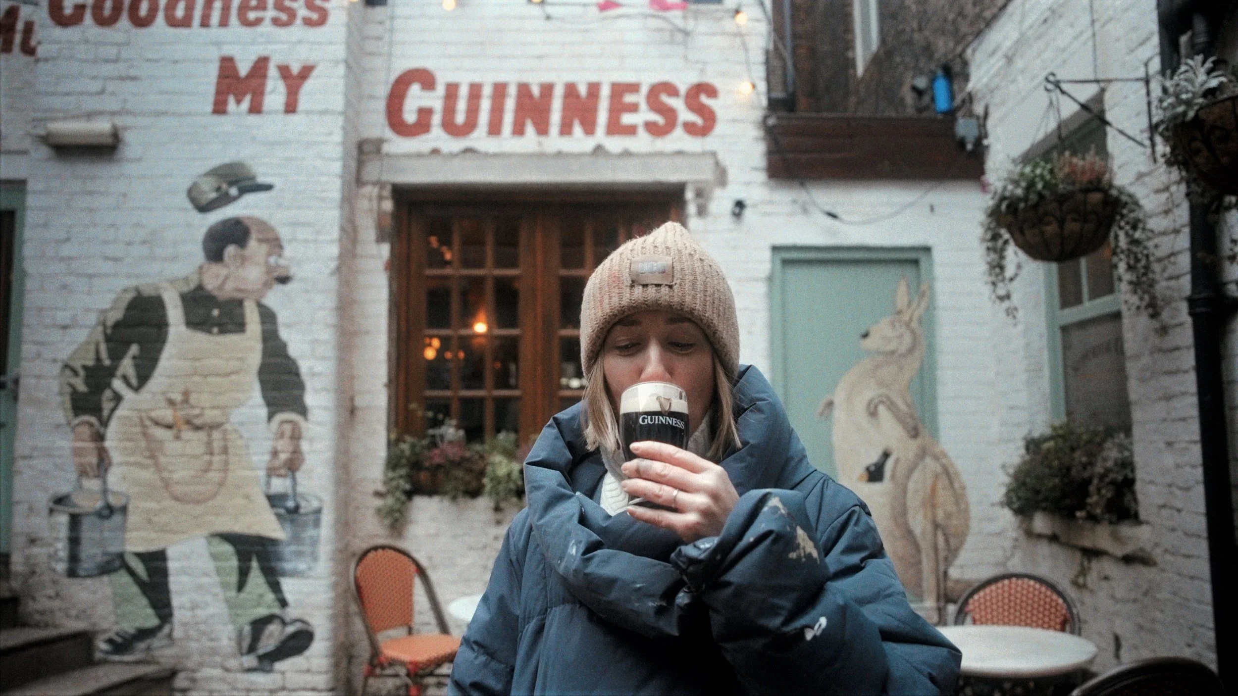 Woman in winter coat outside Guinness pub — candid street lifestyle photography, Liverpool