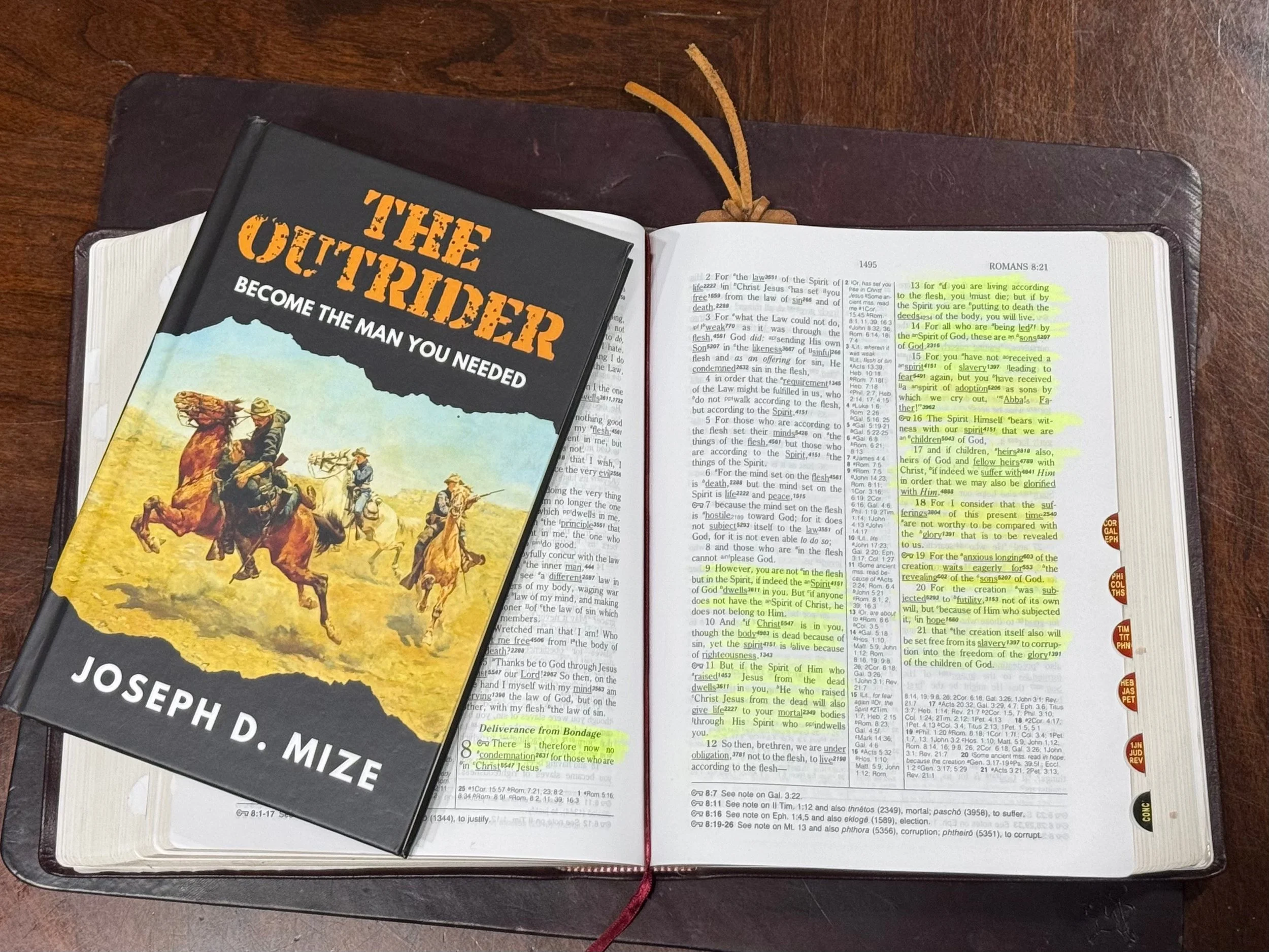 The Outrider book with Bible open to Romans Chapter 8 for The Outrider Devotional and Bible Plan.