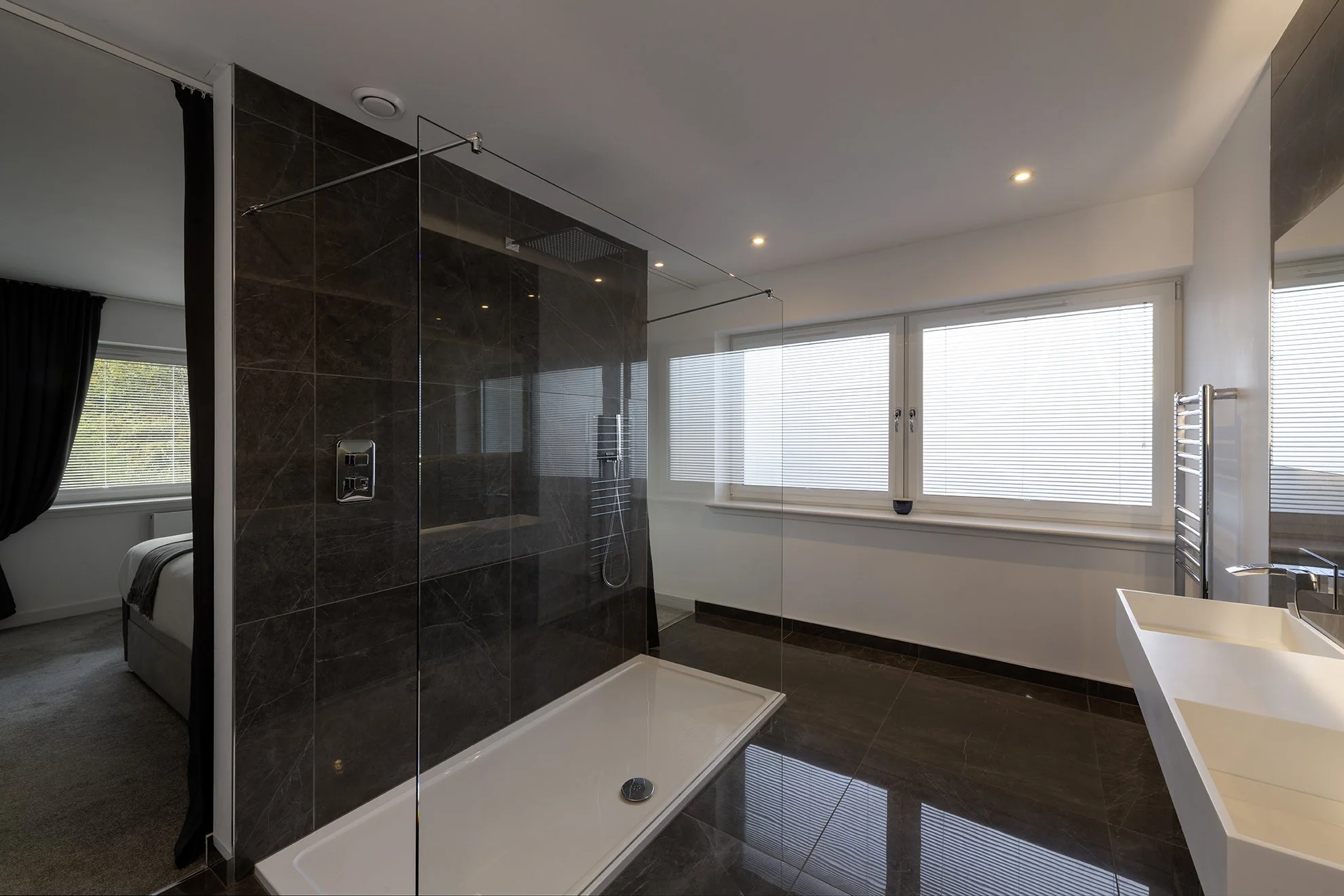 Reflections in the dark tiles of the ensuite shower room enhance the sense of space.