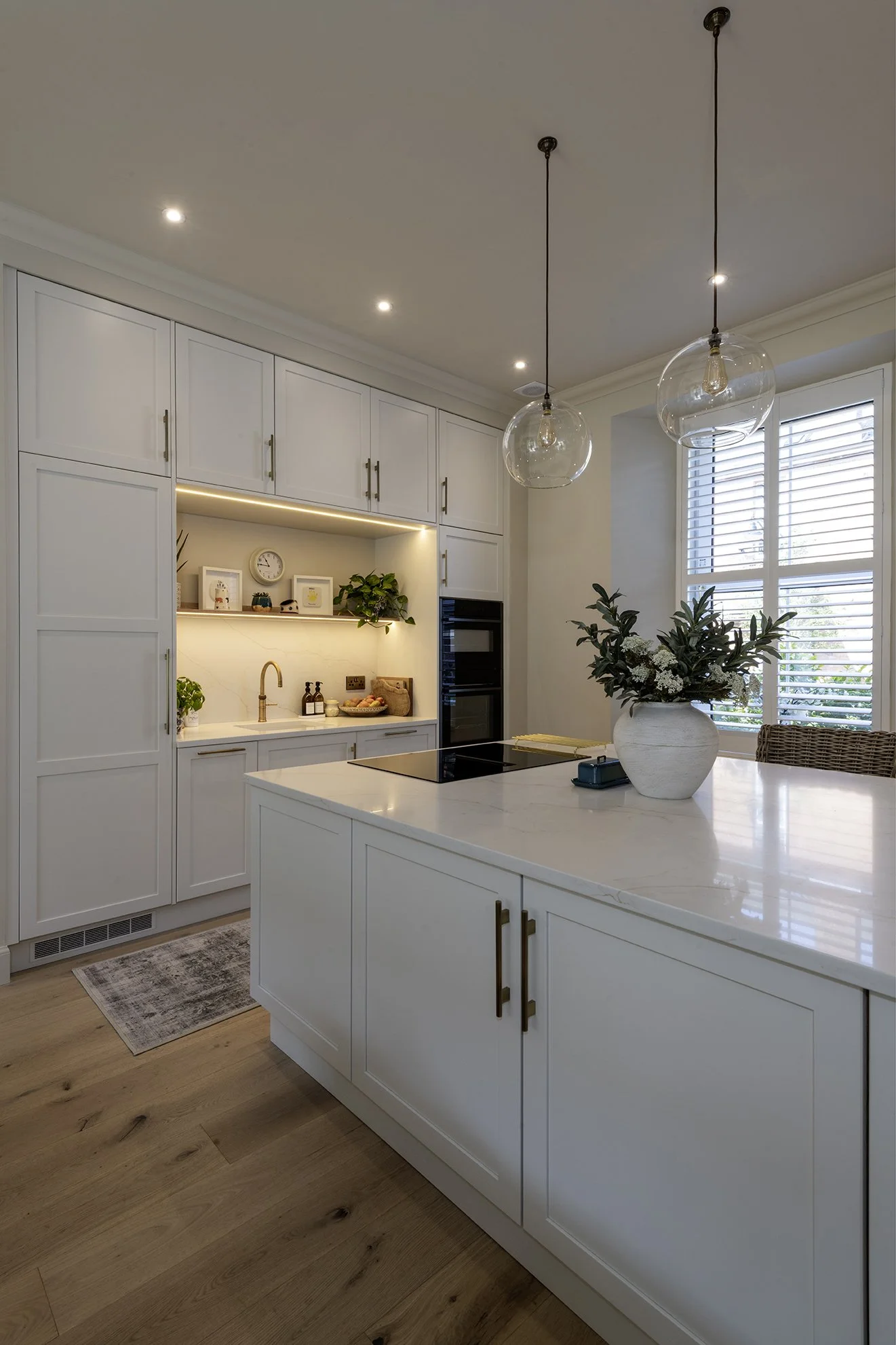 The island is flanked by full height wall units that accommodate other kitchen functions.