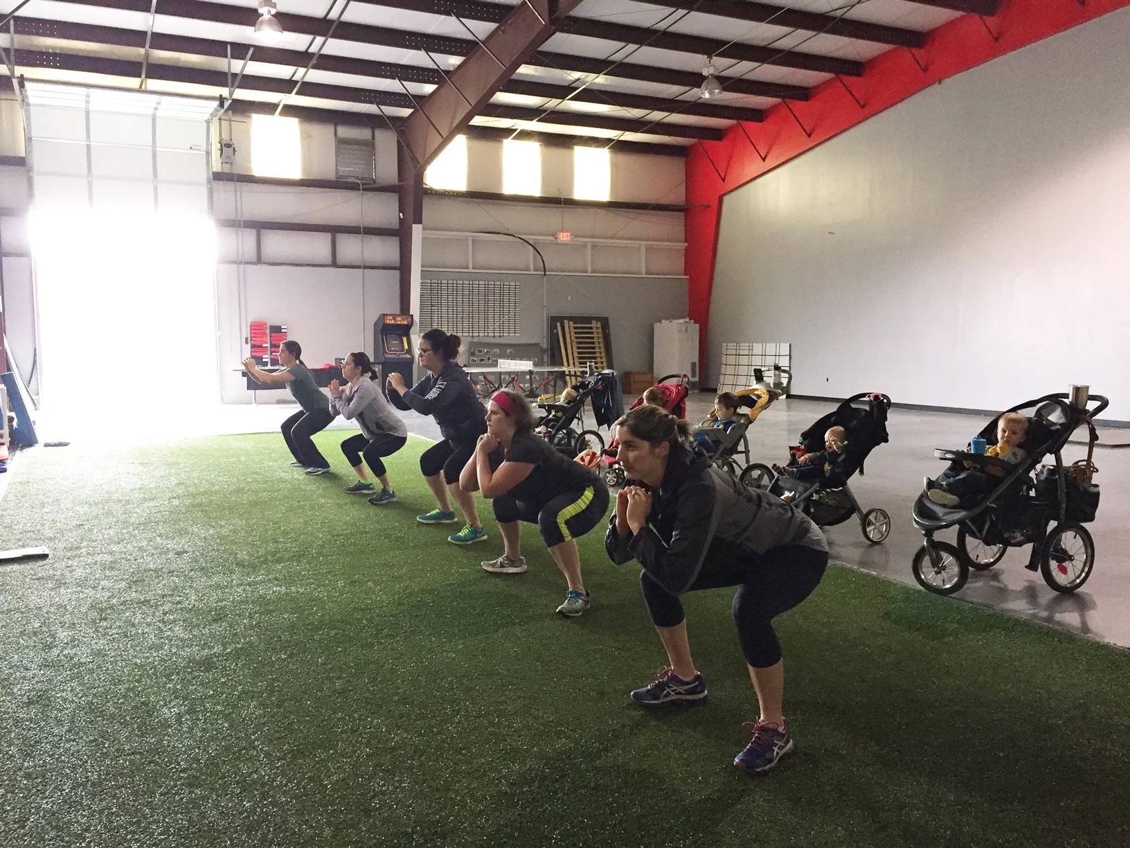 Moms doing bodyweight squats in a fitness class