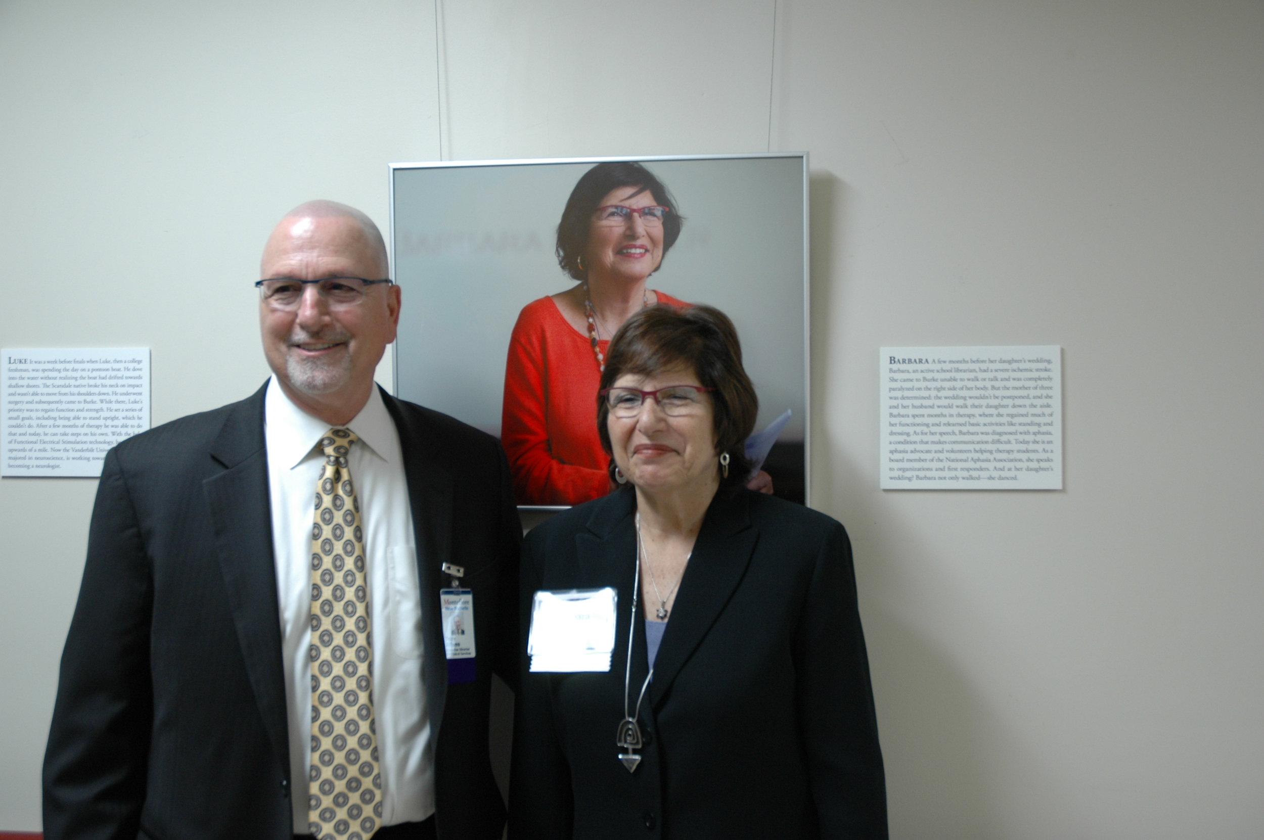Anthony Alfano (left), Vice President and Executive Director at Montefiore New Rochelle, standing with Barbara (right), Faces of Burke participant, in front of her portrait