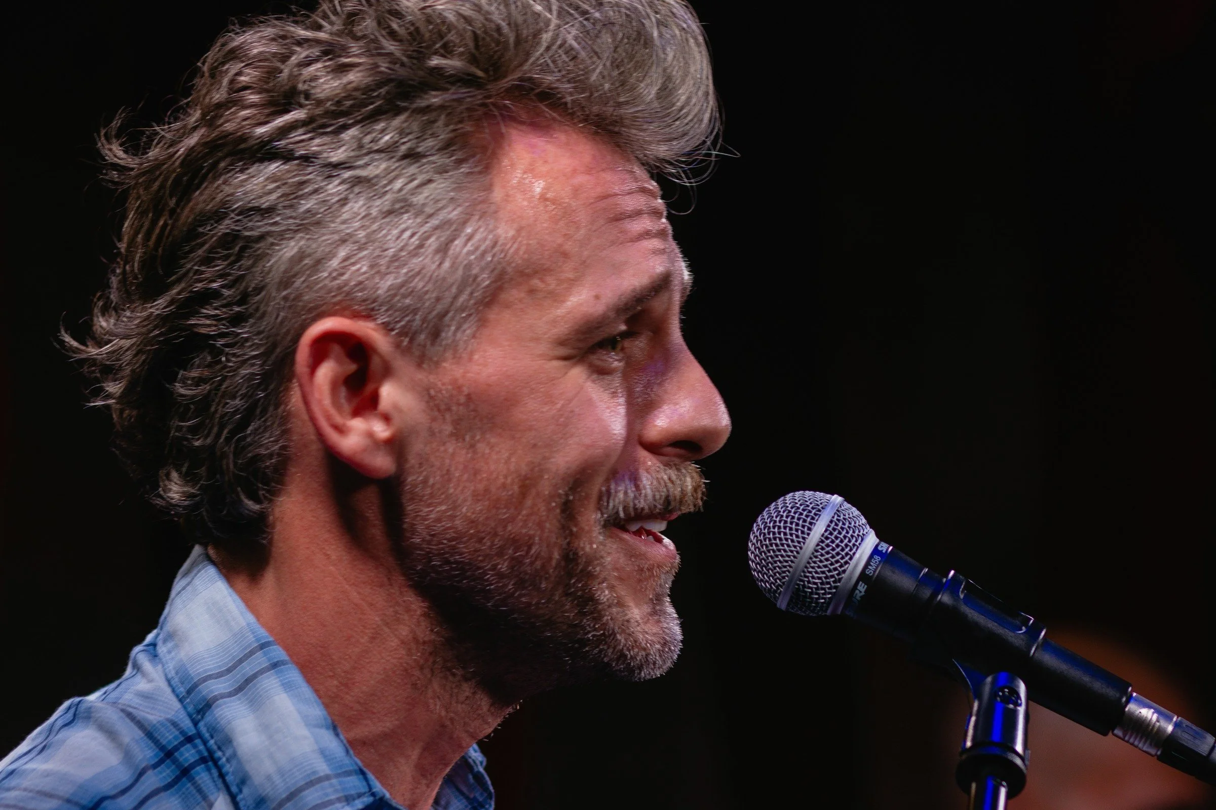Craig Klonowski singing into a microphone live at The Duplex in New York.