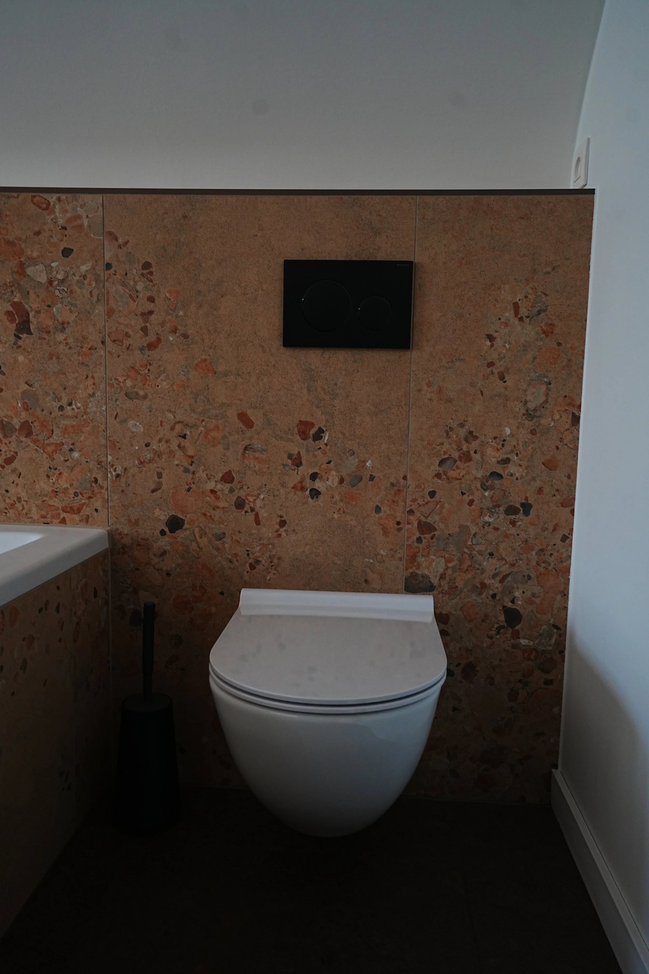 Modern toilet met een op maat gemaakte bak in een badkamer met natuurstenen tegels op de muur.