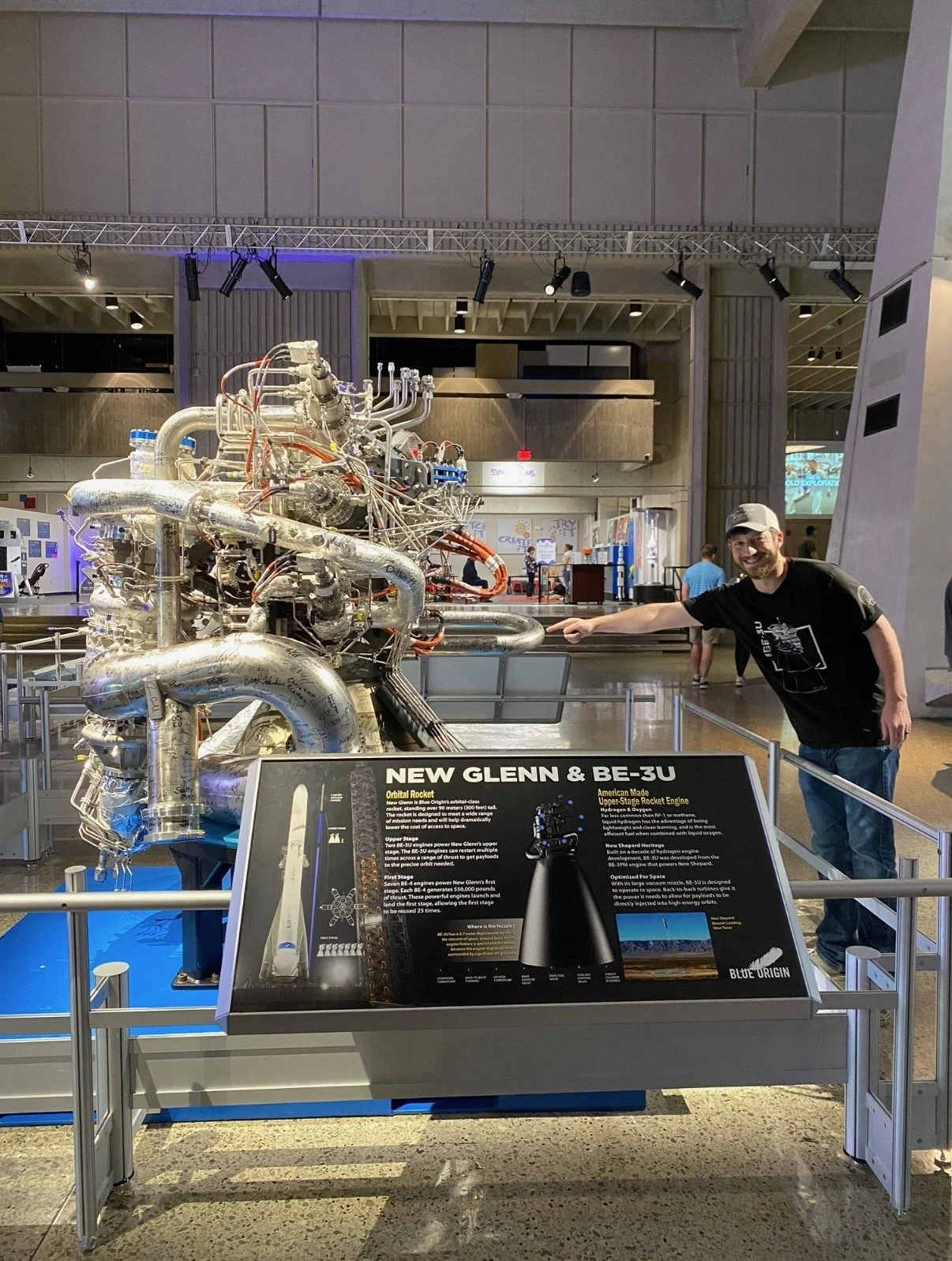 Travis Davis pointing at the Blue Origin New Glenn rocket display inside the Space and Rocket Center in Huntsville, AL.