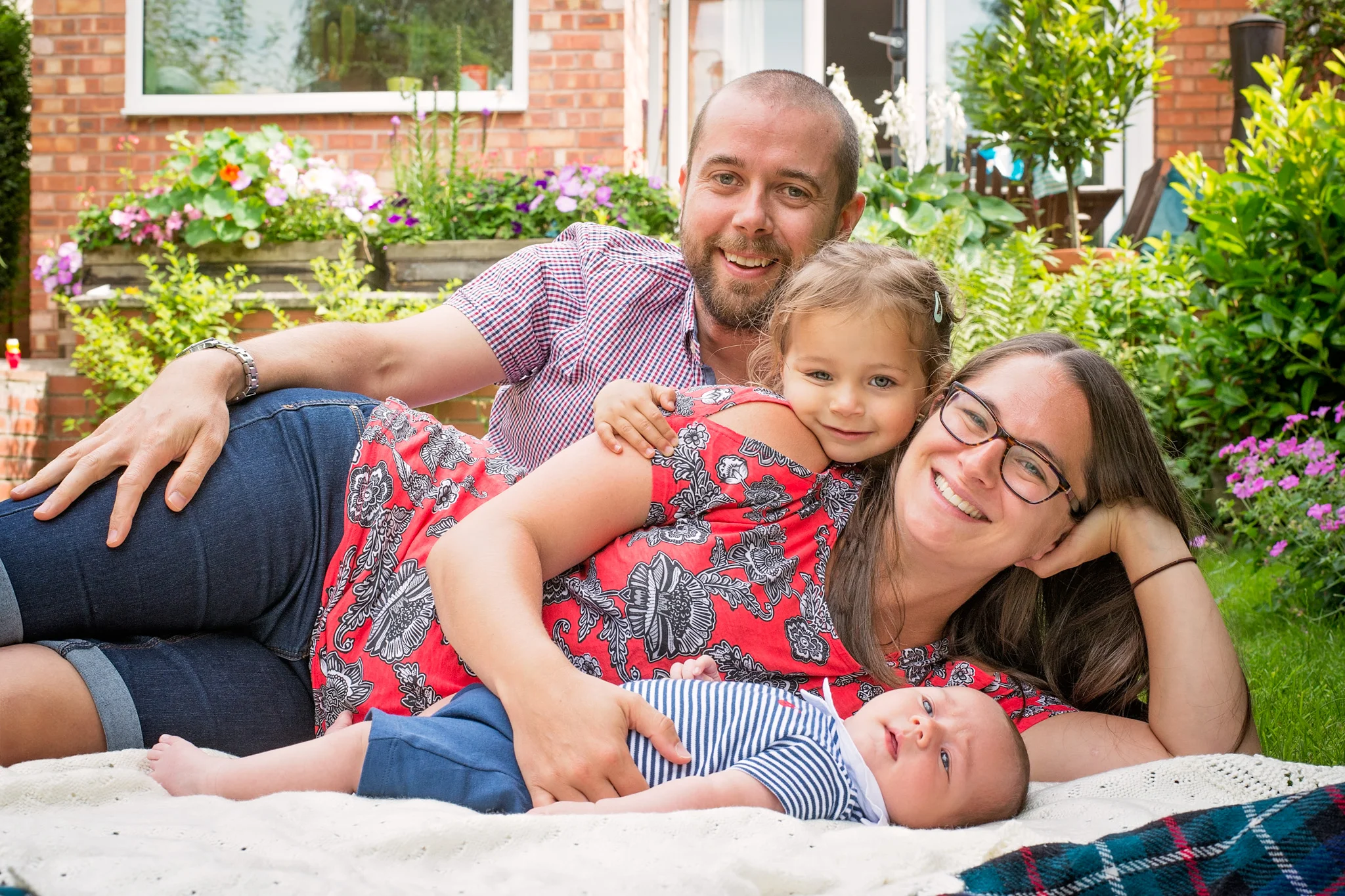 Family lounging on rug in the garden | Warwickshire Photographer