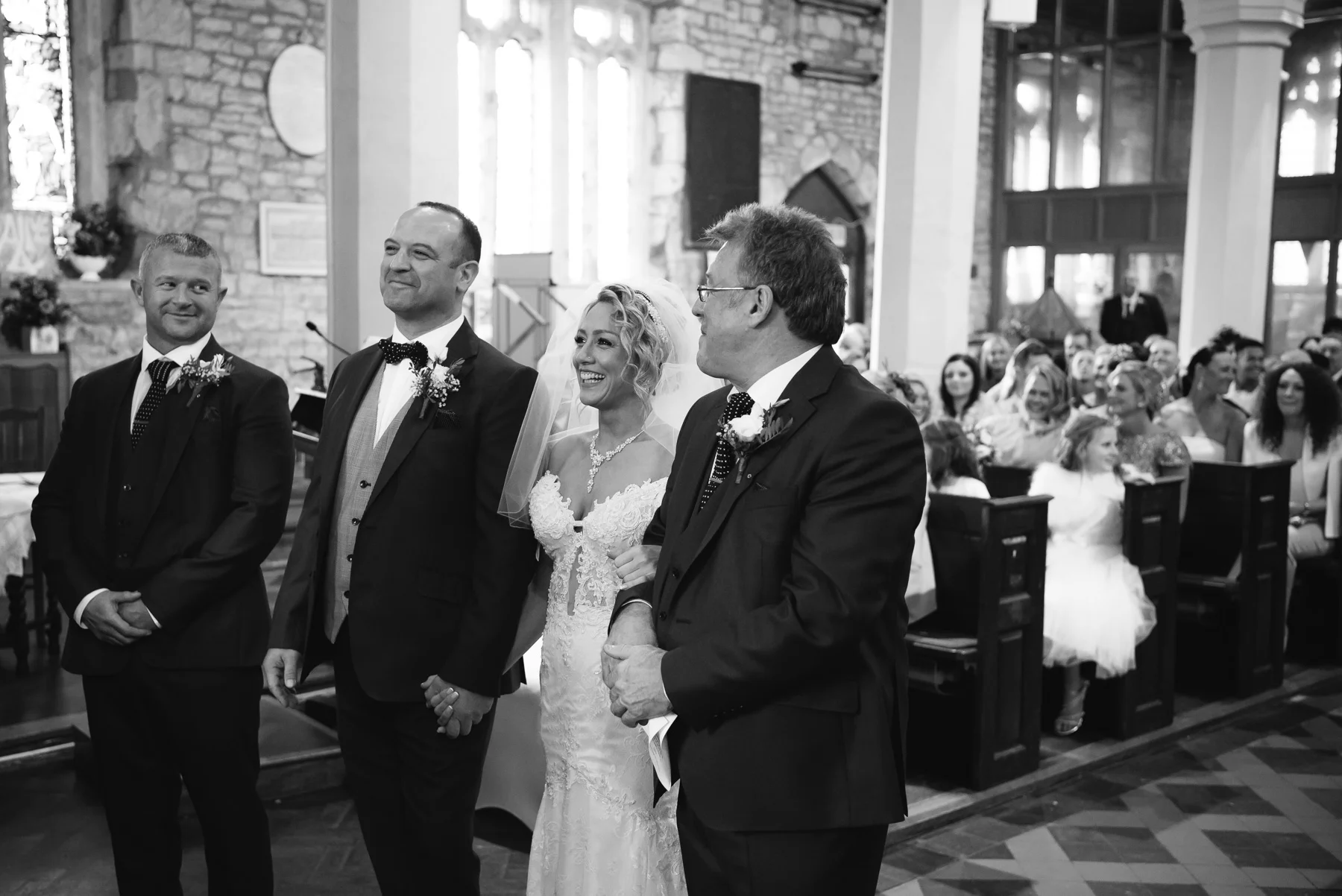Couple smiling with best man and father of the bride during church ceremony | Warwickshire Wedding Photographer