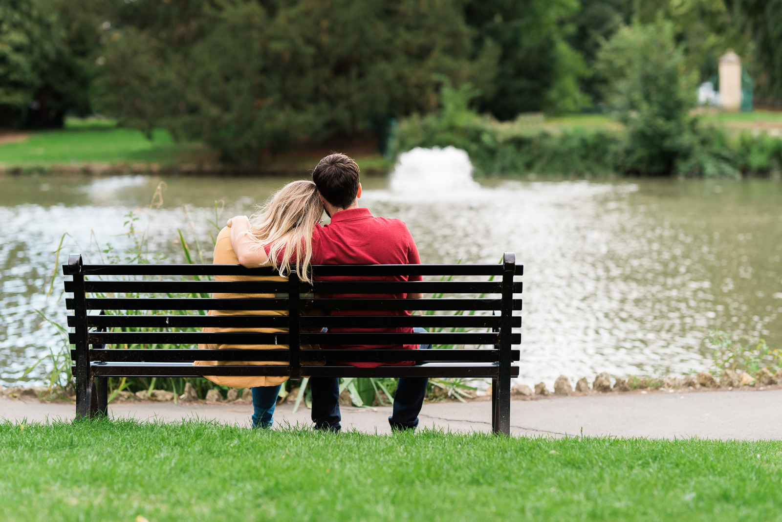 Couple cuddling on a bench at Pittville Park - Cotswolds Wedding Photographer
