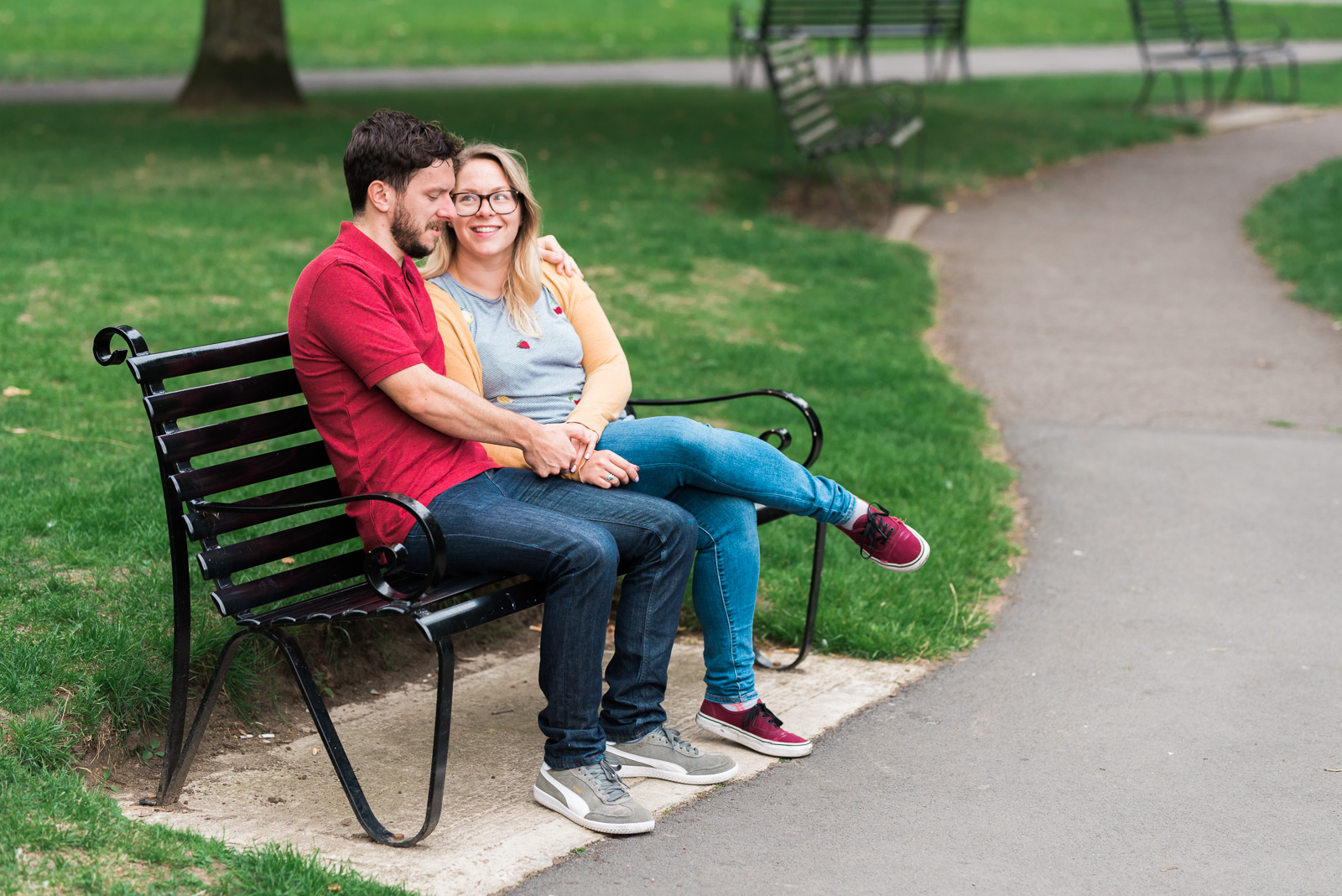 Engaged couple laughing on a bench - Cotswolds Wedding Photographer