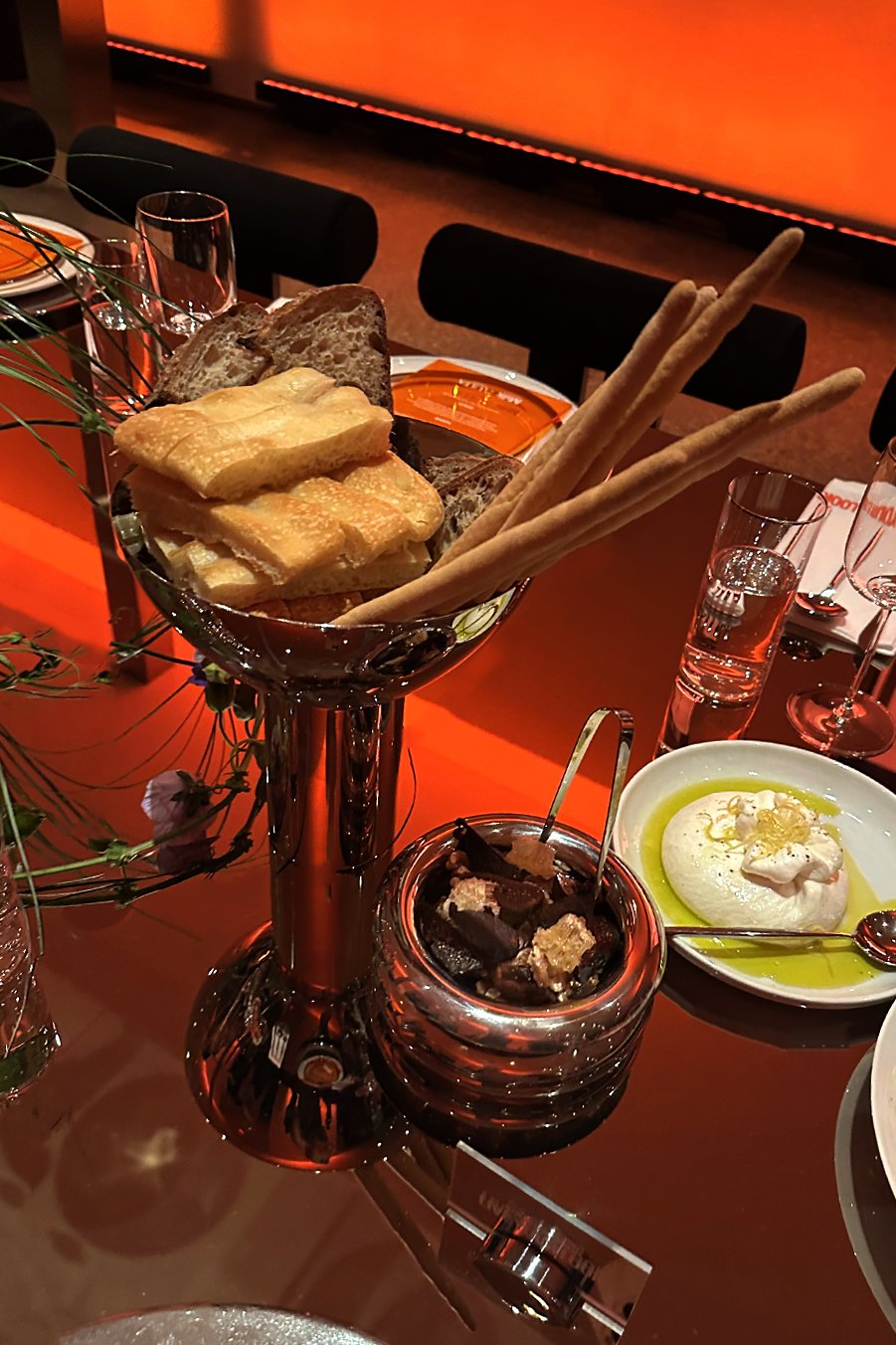 Italian bread assortment with golden focaccia, rustic country loaf, and grissini breadsticks served alongside burrata with lemon zest and a bowl of honeycomb and dried figs. Part of Cava & Cake’s antipasto trio for the Milk Makeup x Ulta Beauty dinne
