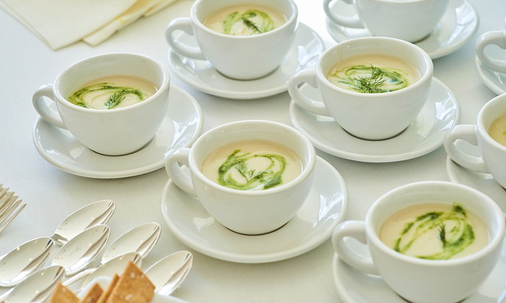 Indulge in the creamy elegance of Jerusalem Artichoke Soup (Sunchoke Soup) by Cava & Cake, served in latte cups and topped with green herb oil at a stunning Beverly Hills luncheon.