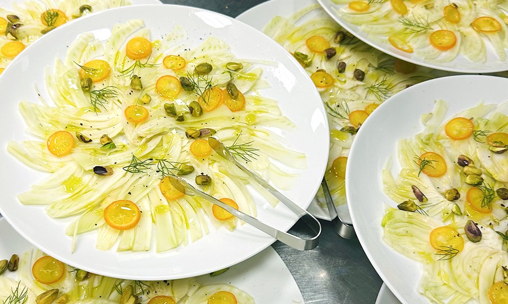 Fennel carpaccio with sliced kumquats, and roasted pistachios. A vibrant vegan appetizer by Cava & Cake for the Milk Makeup x Ulta Beauty dinner at Milk Studios Los Angeles, showcasing California spring produce with Italian flair.