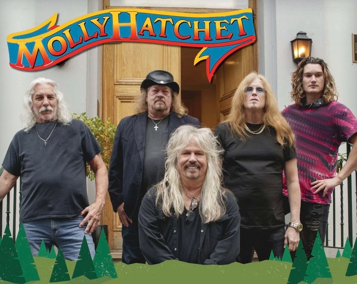 Molly Hatchet band members pose beneath the colorful Molly Hatchet logo outside Inn of the Mountain Gods.