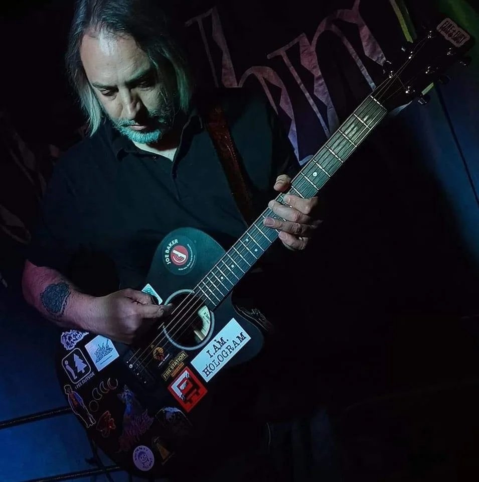 Singer-songwriter Richard Nihil of I Am Hologram performing with an acoustic guitar.