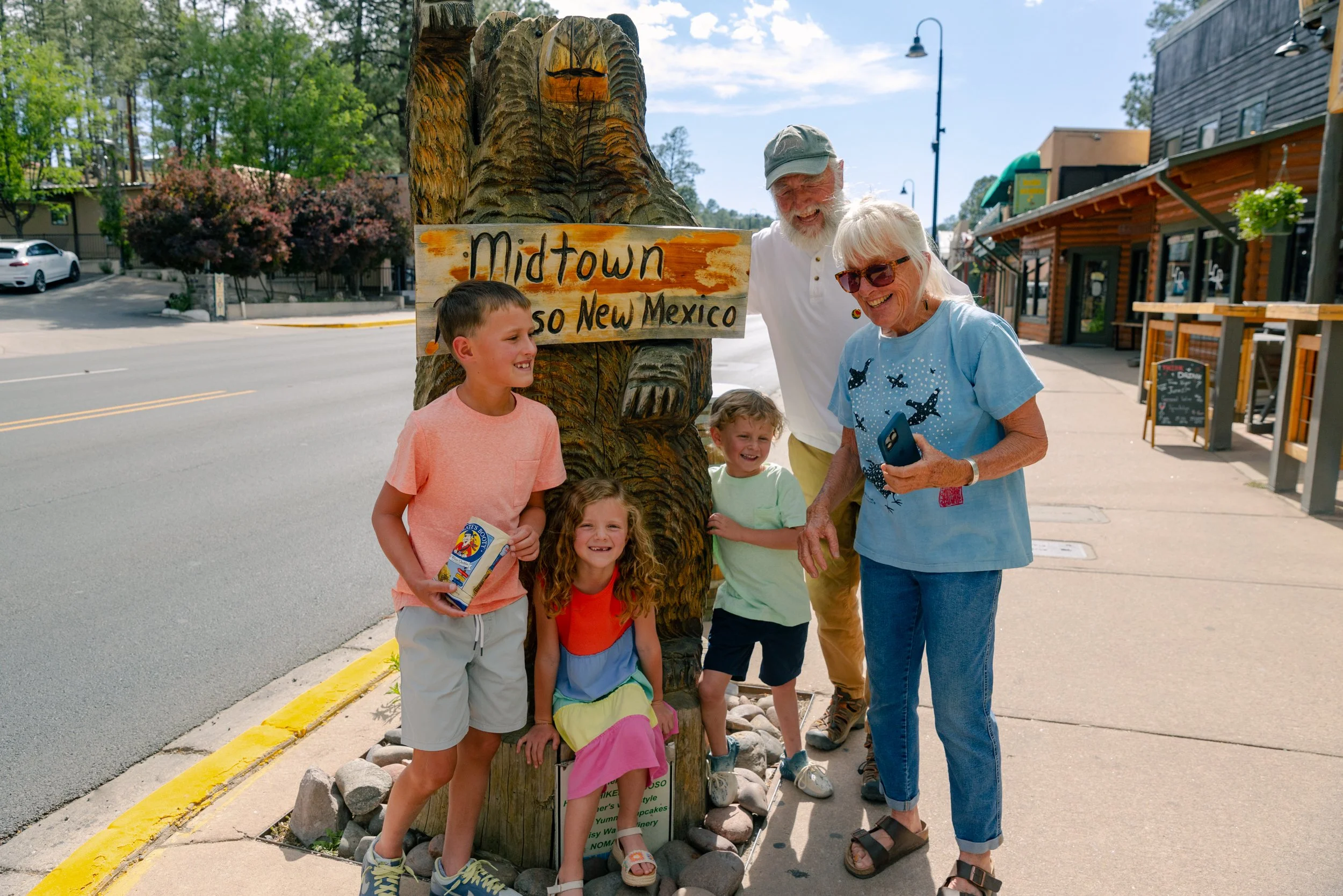 Multigenerational family posing with carved bear in Midtown Ruidoso, NM