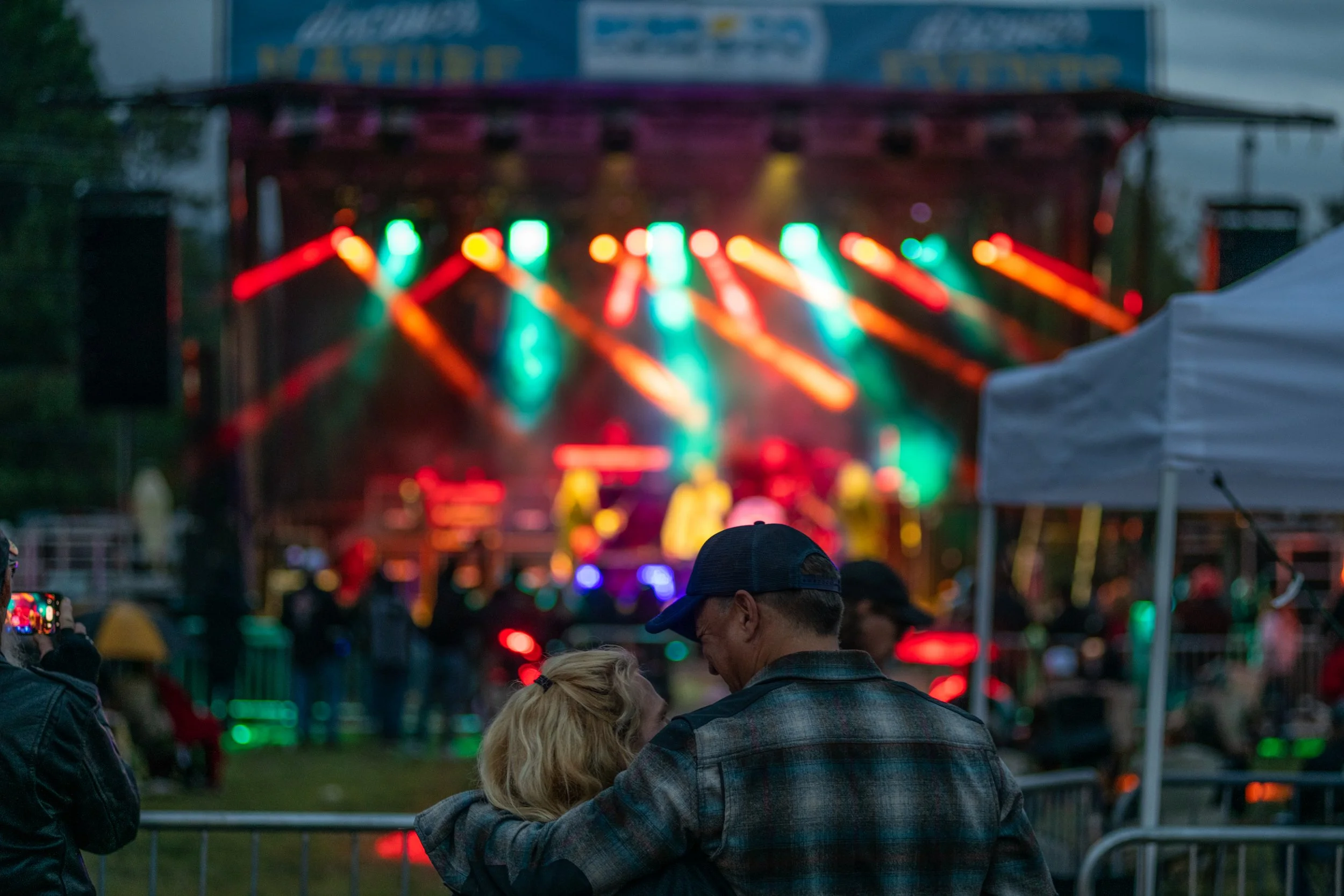 Couple watching an outdoor concert in Ruidoso with colorful stage lights in the background