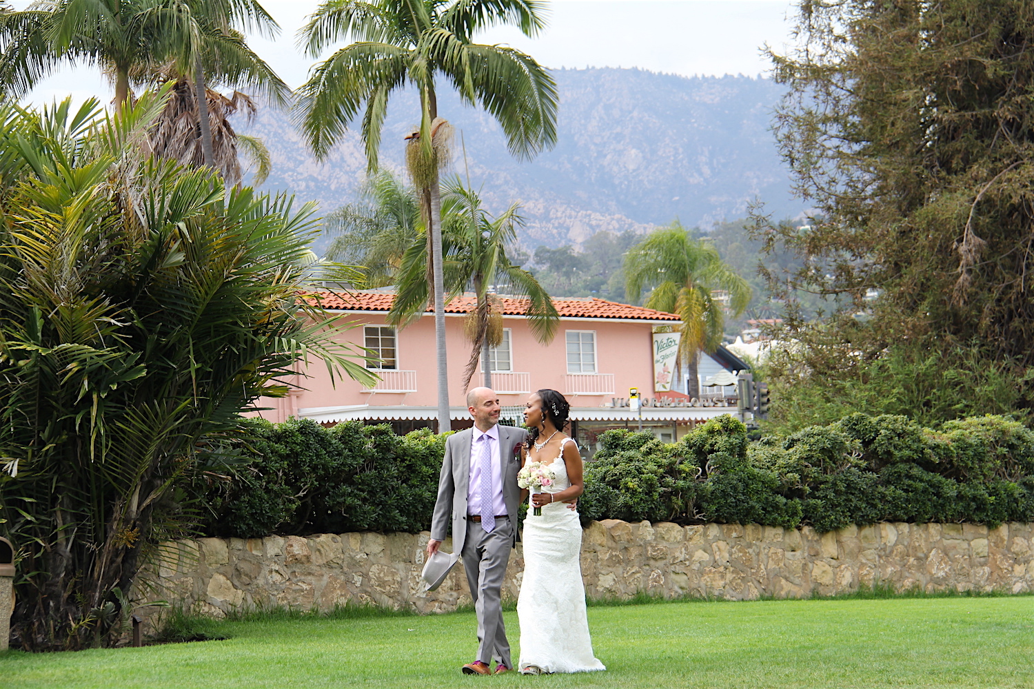 bride and groom walk on expansive garden lawn at courthouse in SB