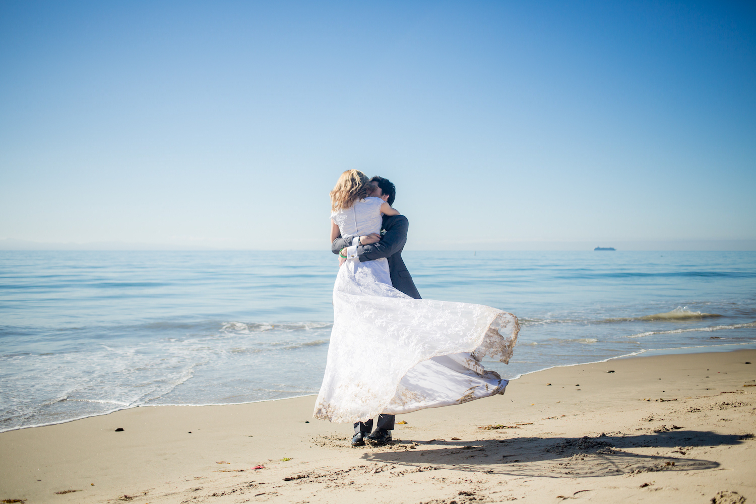 groom twirling bride around on Santa Barbara beach