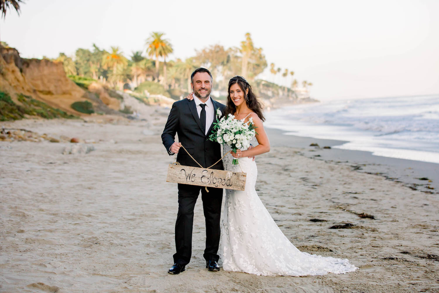  couple holding “We Eloped” sign on the Santa Barbara beach 
