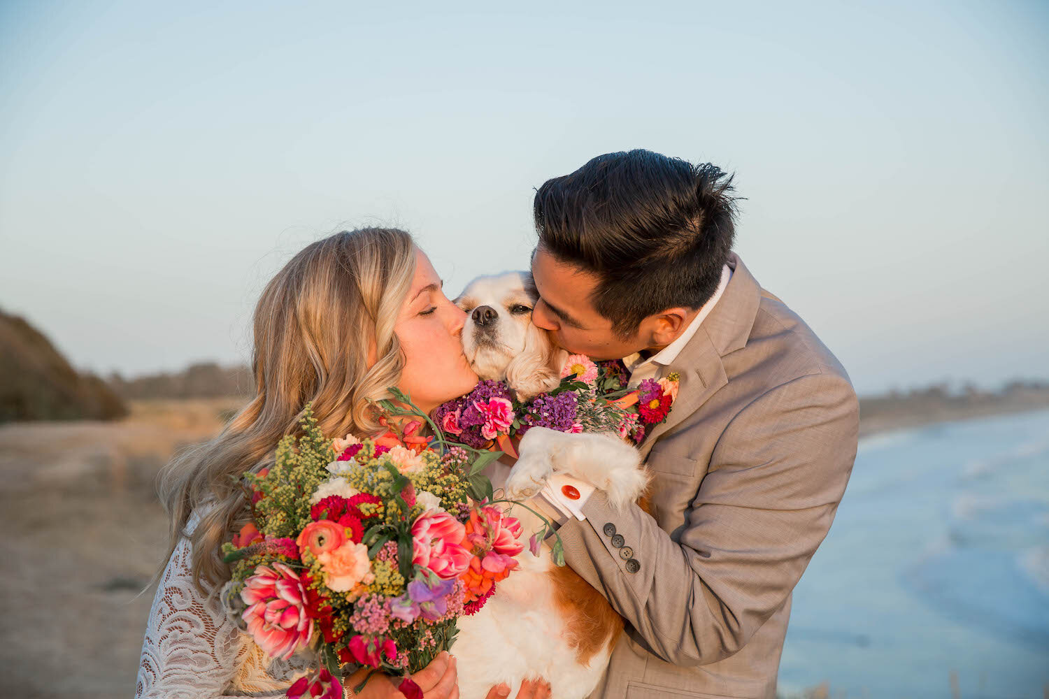  couple kiss their dog on the beach 