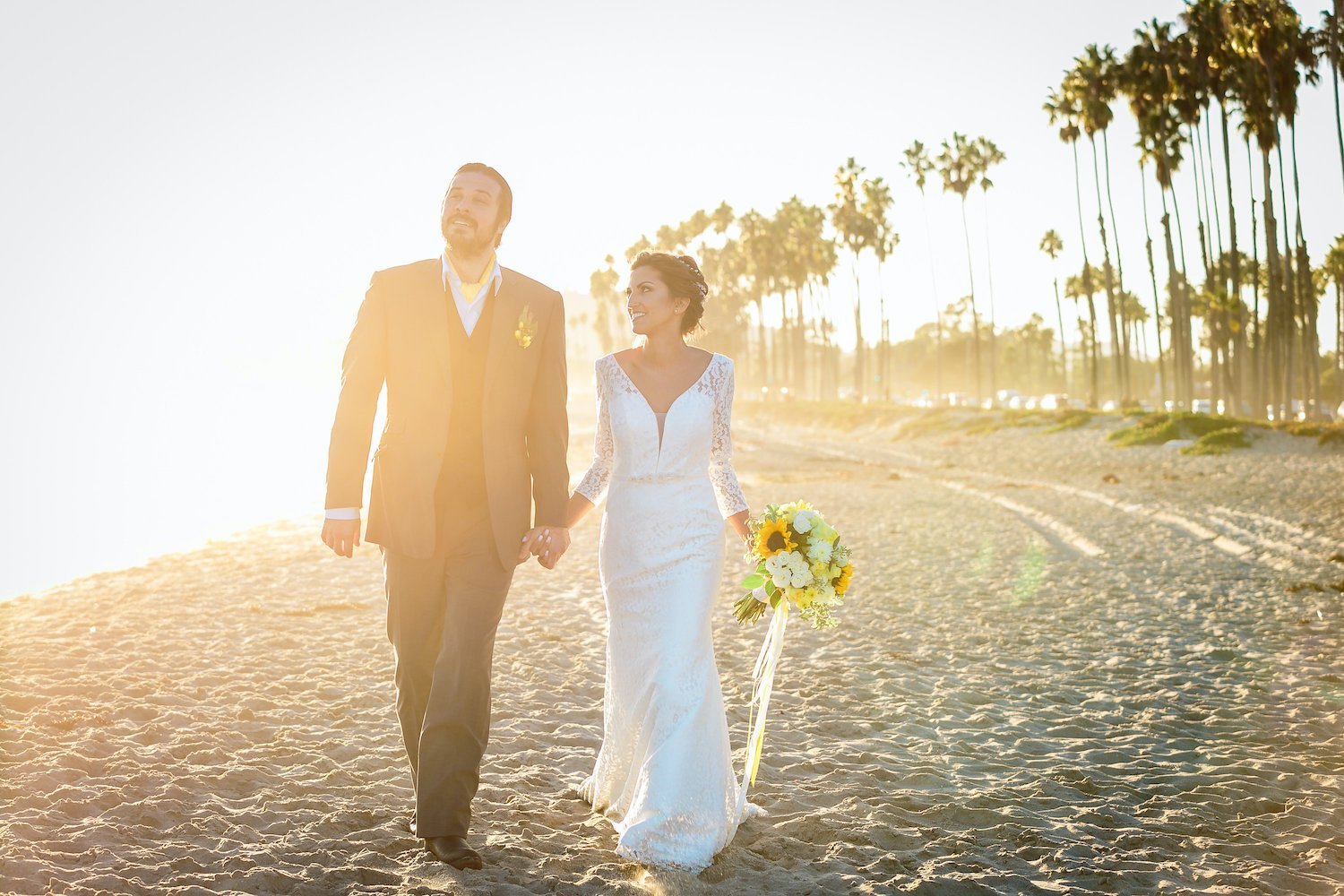  bride and groom walk hand in hand on Santa Barbara beach at sunset 