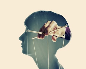 Silhouette of a woman's profile and within the woman's head is a man's hand holding marionette strings.