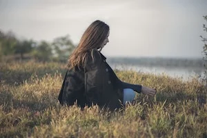 Woman with long brown hair sitting in a field